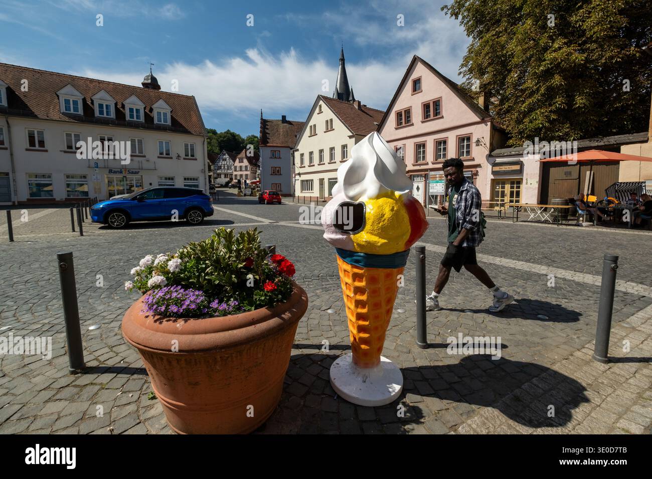 19.08.2025, Deutschland, Saarland, Ottweiler (Saar) - Rathausplatz in der Altstadt mit Skulptur von Eiskugeln auf einem Waffelkegel von einem Italiener Stockfoto