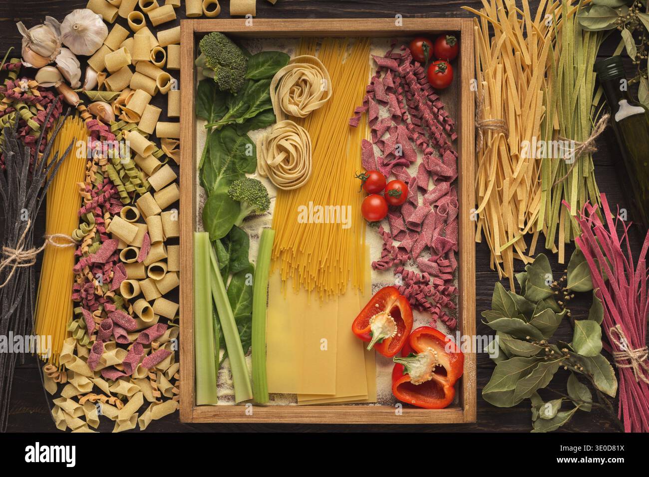 Collage aus verschiedenen Pasta- und Gemüsesorten, die in einem Holztablett mit bunten Details angeordnet sind Stockfoto