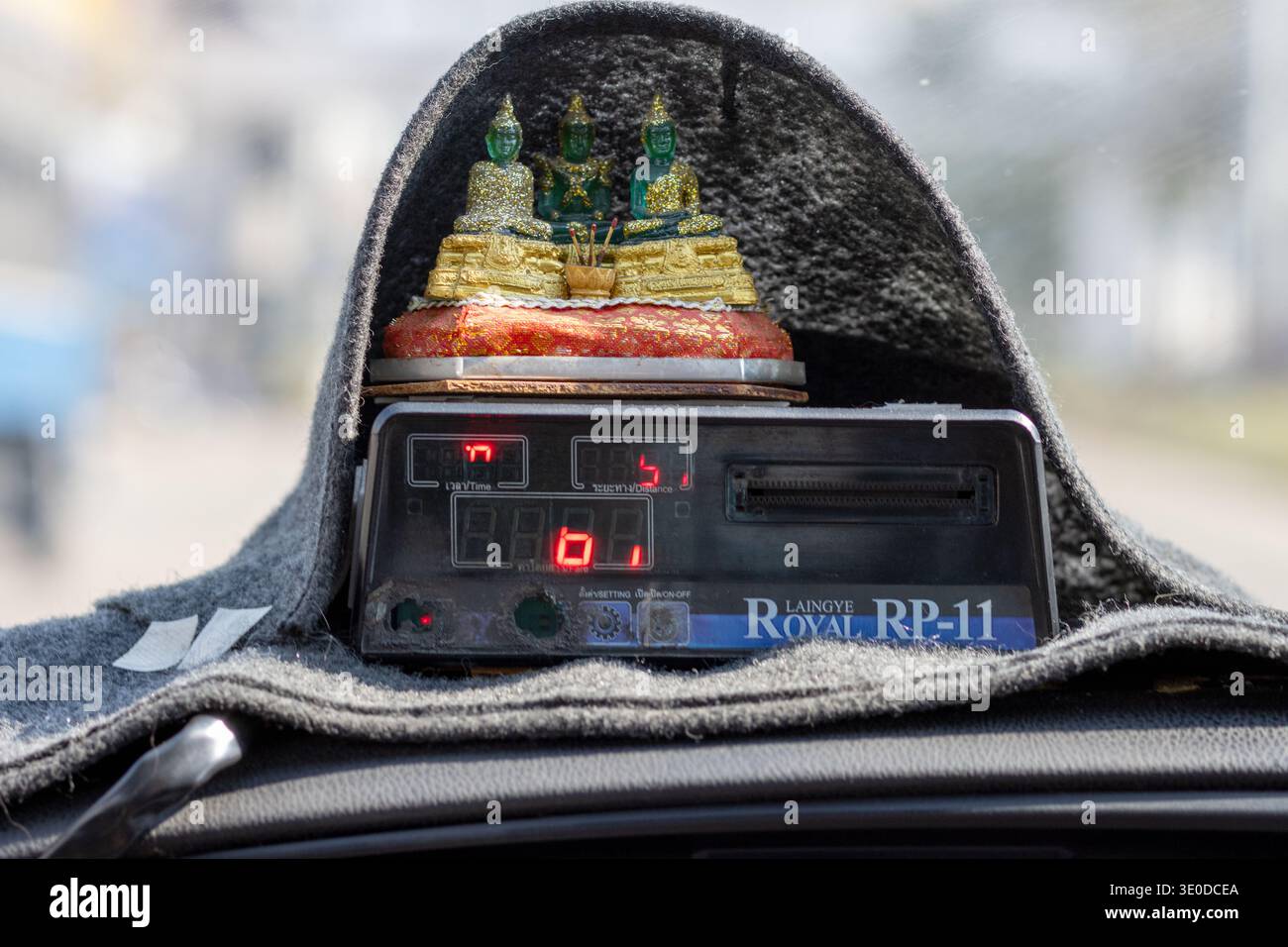 BANGKOK, THAILAND, 17. JAN 2026, Innenansicht eines Taxameters mit kleinen Buddha-Statuen auf dem Armaturenbrett in einem fahrenden Bangkok Taxi Stockfoto