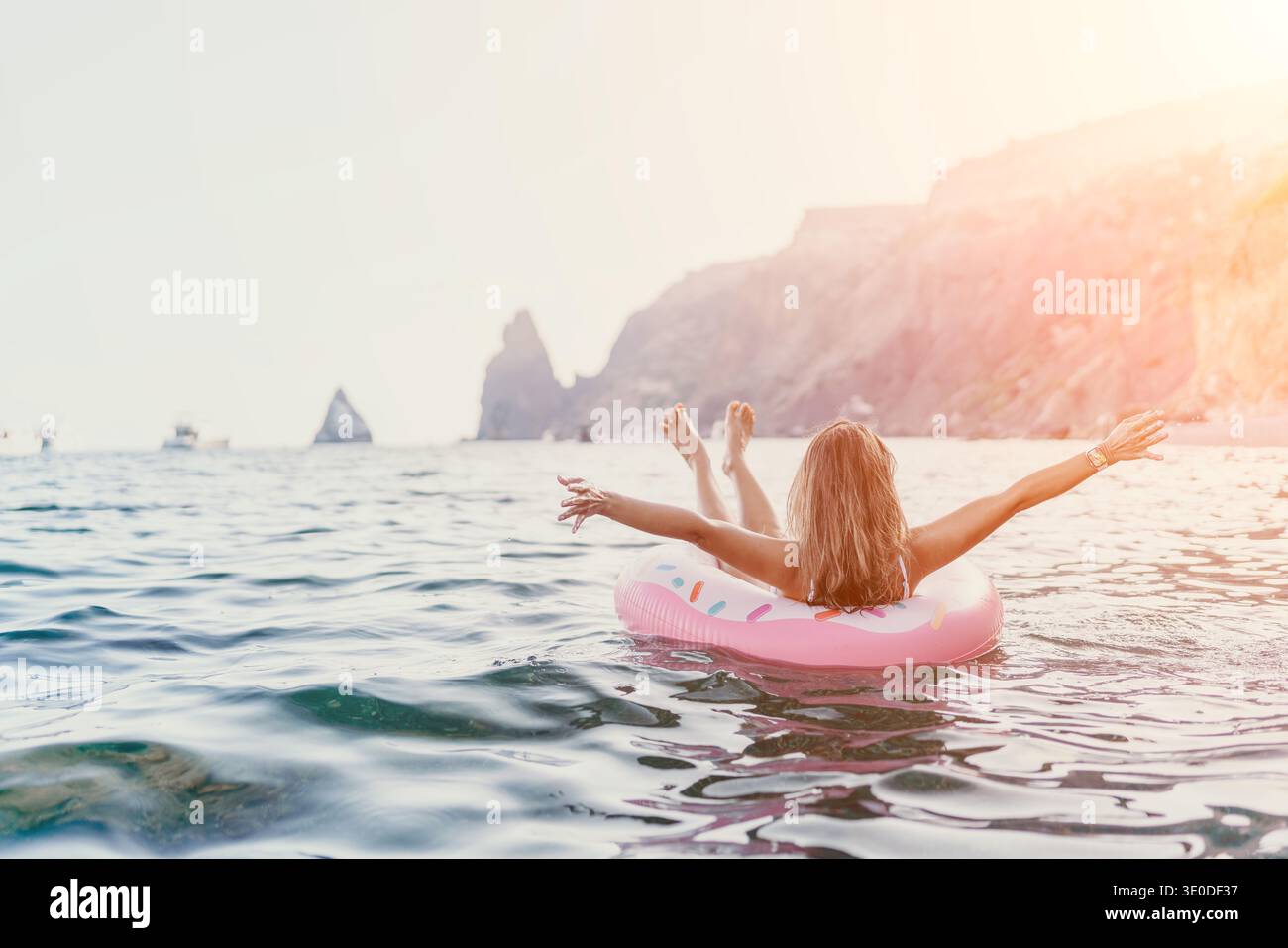 Frau, Meer, entspannend. Blonde Frau schwimmt auf Donut-Ring in ruhigen Meeresgewässern und genießt Sommerurlaub mit viel Kopierraum. Stockfoto