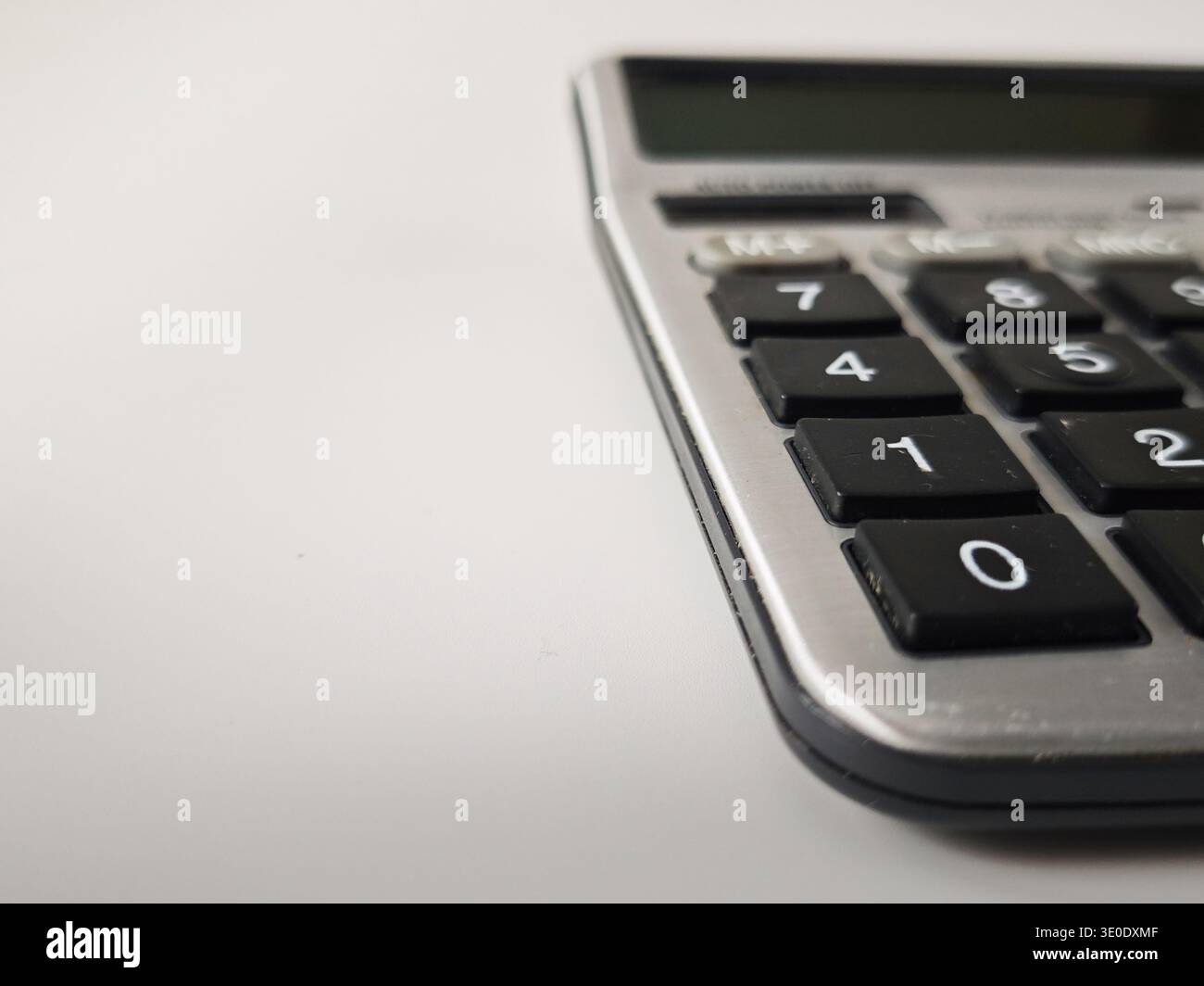 Ein Taschenrechner zeigt Zahlen und Schaltflächen auf einer Oberfläche an, während jemand zu Hause oder im Büro berechnet. Stockfoto