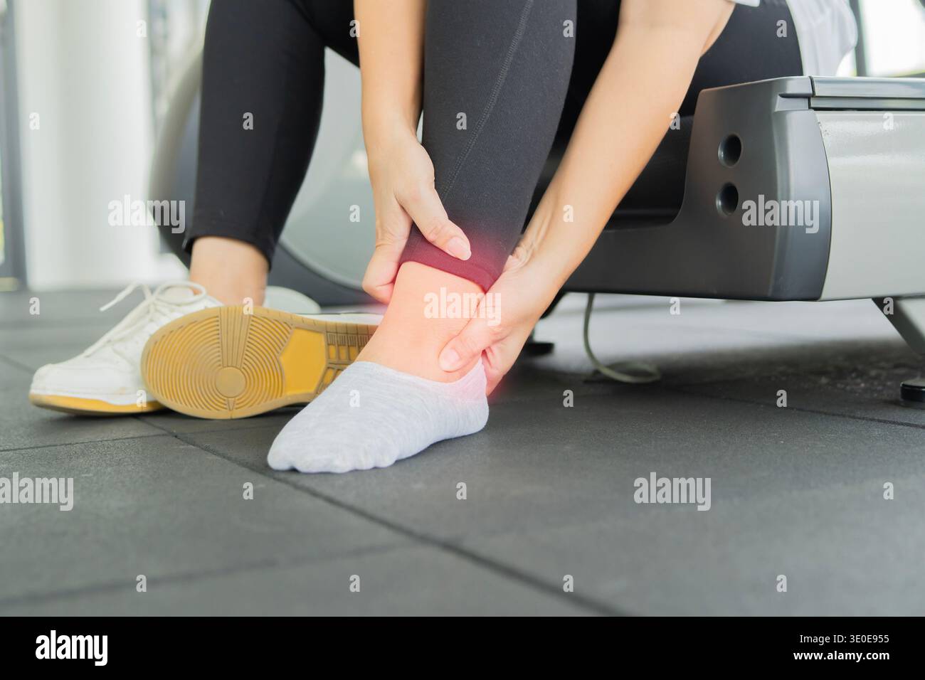 Frau mit Schmerzen beim Laufen im Fitnessstudio, Knöchelverletzung. Ältere Frau mit einem Ausdruck starker Schmerzen im Knöchel. Athletin Frau hat Wadenkruste, Schmerzen in A Stockfoto