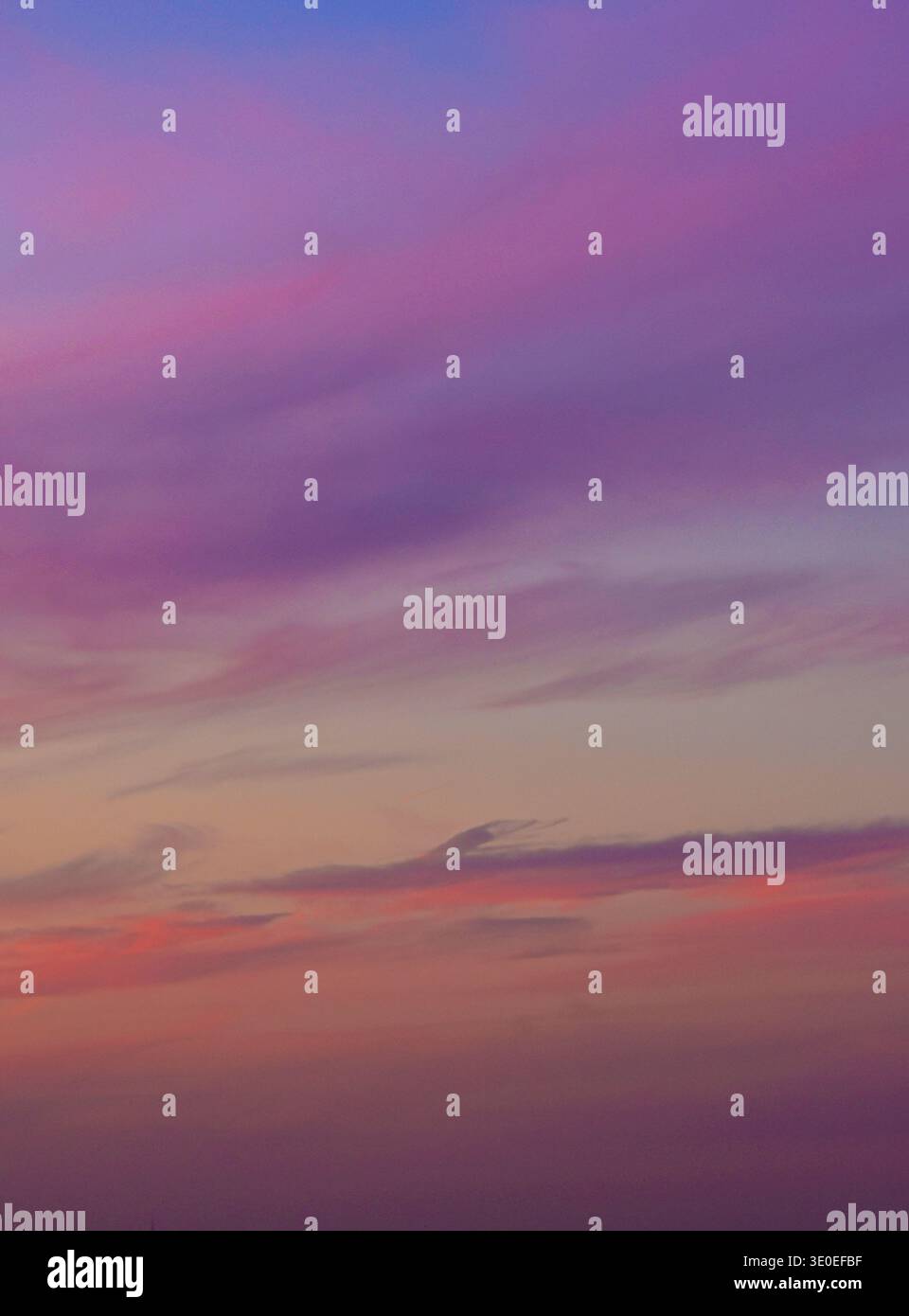 Ein ruhiger und minimalistischer Abendhimmel mit sanften Violetttönen und sanften Orangengradienten mit zarten Wolkenstrukturen Stockfoto