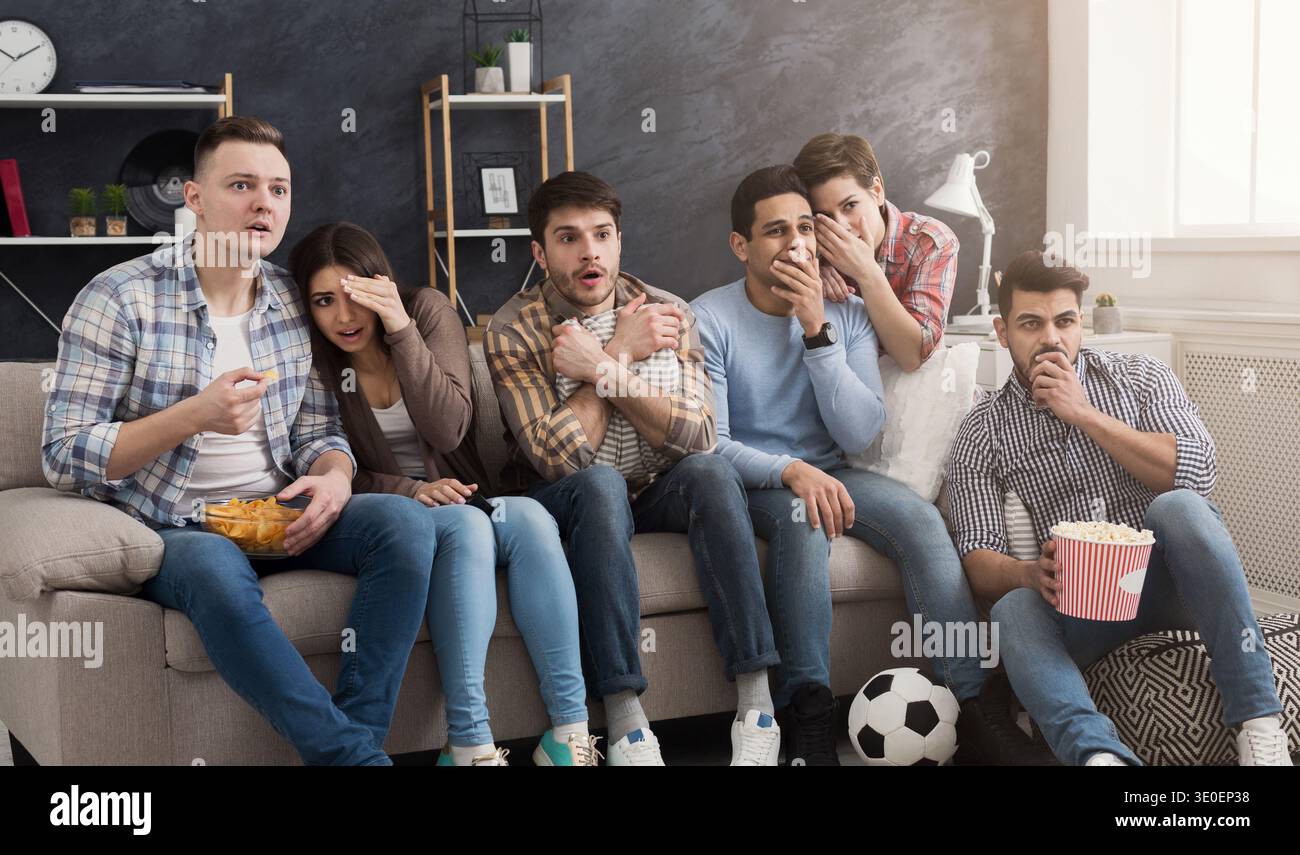 Schockierte multiethnische Freunde, die zu Hause Filme sehen Stockfoto