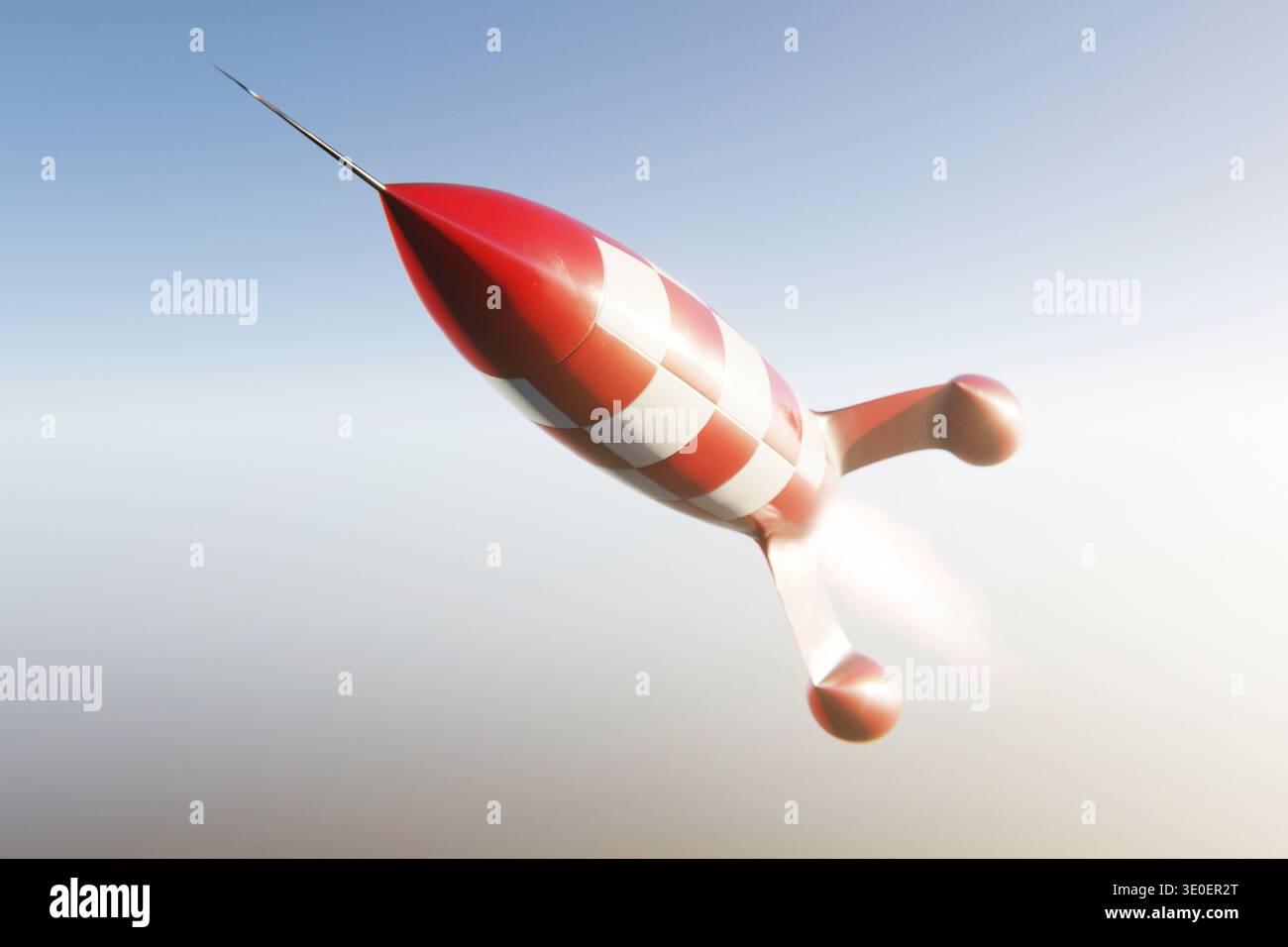 Rot-weiß karierte Rakete im Vintage-Stil, die durch einen klaren Himmel fliegt. Retro-Weltraumforschung, Science-Fiction-Raketenschiff und kreative Ae Stockfoto