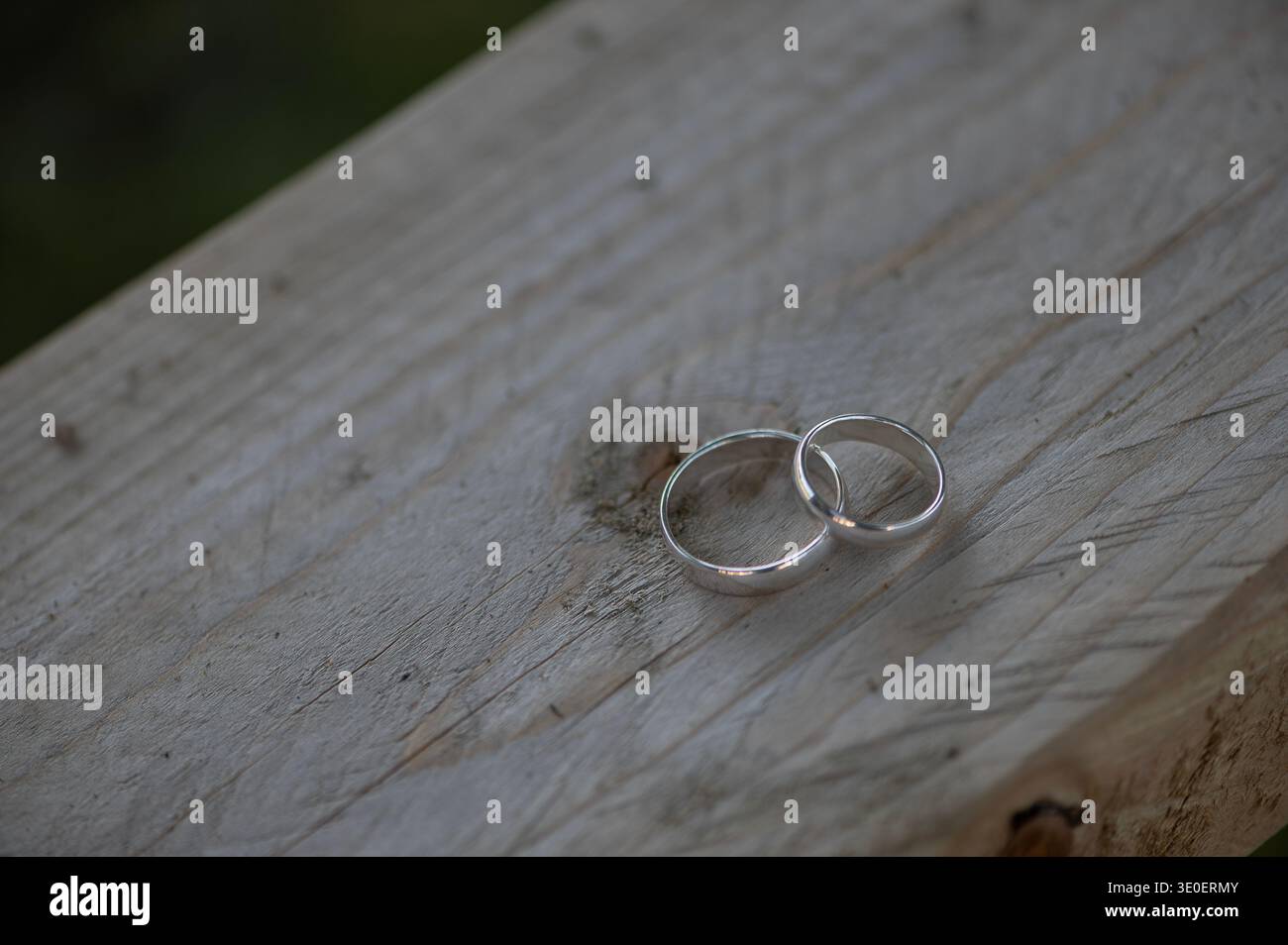 Zwei einfache silberne Eheringe auf rustikaler Holzoberfläche symbolisieren zeitloses Engagement und Einheit. Stockfoto