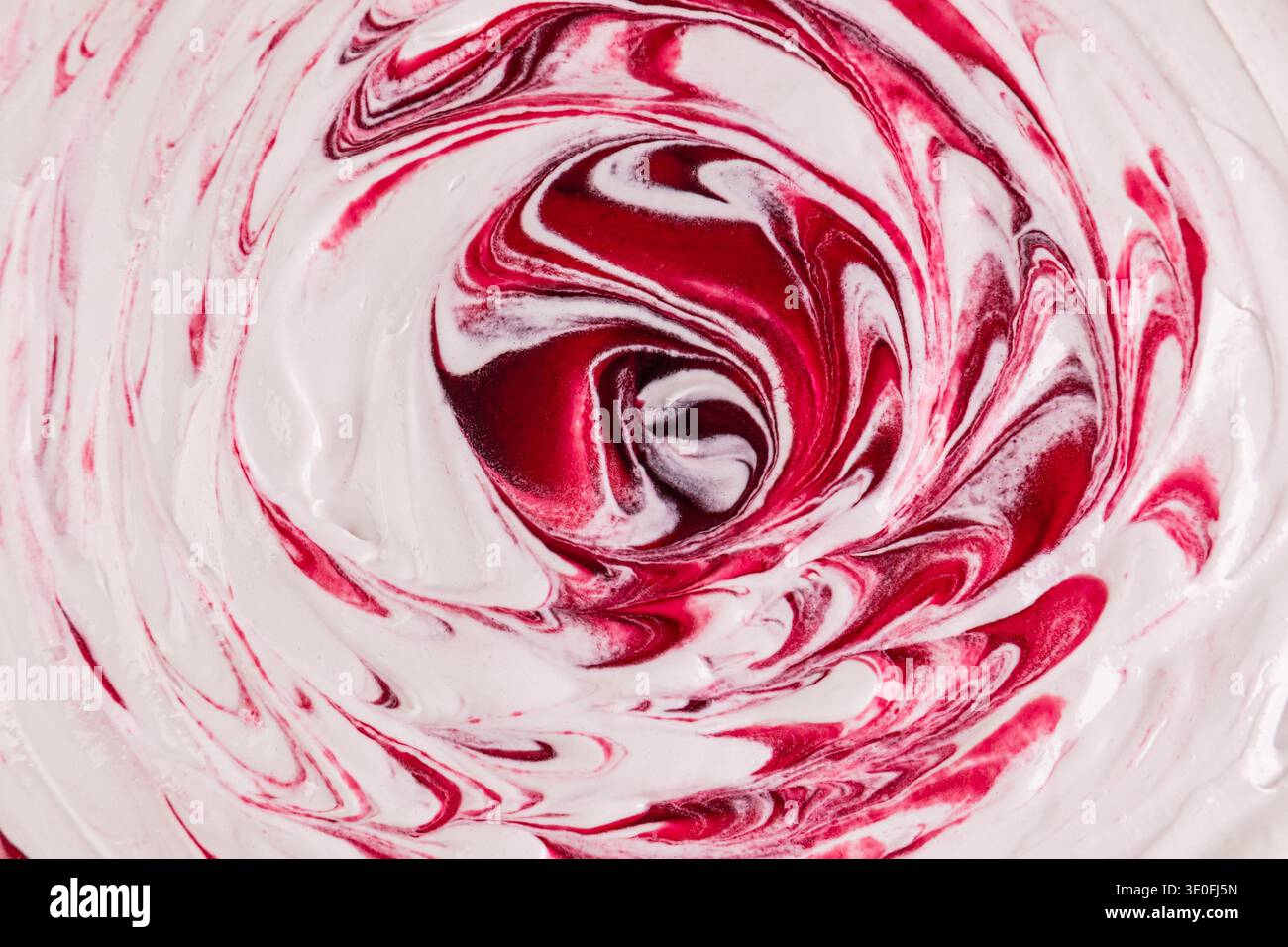 Ein heller saftiger Hintergrund aus Buttercreme mit Kirschsirup oder Marmelade. Große Locken beim Schlagen der Sahne mit einem Schneebesen. Draufsicht. Selektiver Fokus Stockfoto