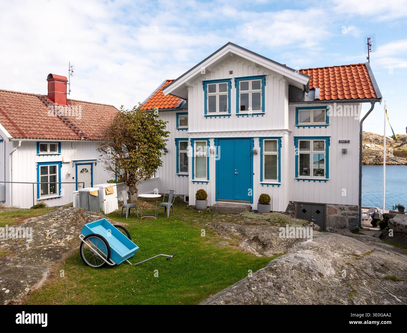 Weißes Holzhaus mit blauer Zierleiste auf felsigem Grund am Wasser auf der Insel Gullholmen in Bohuslän, Westküste Schwedens Stockfoto