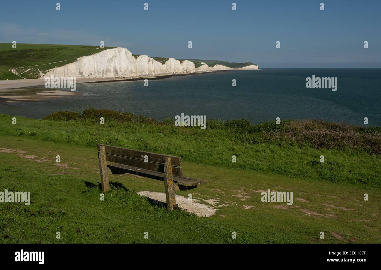 Holzbank am Rande eines Fußweges am Seaford Head mit Blick auf den Ärmelkanal, Beachy Head und die weißen Kreidefelsen der Seven Sisters Stockfoto