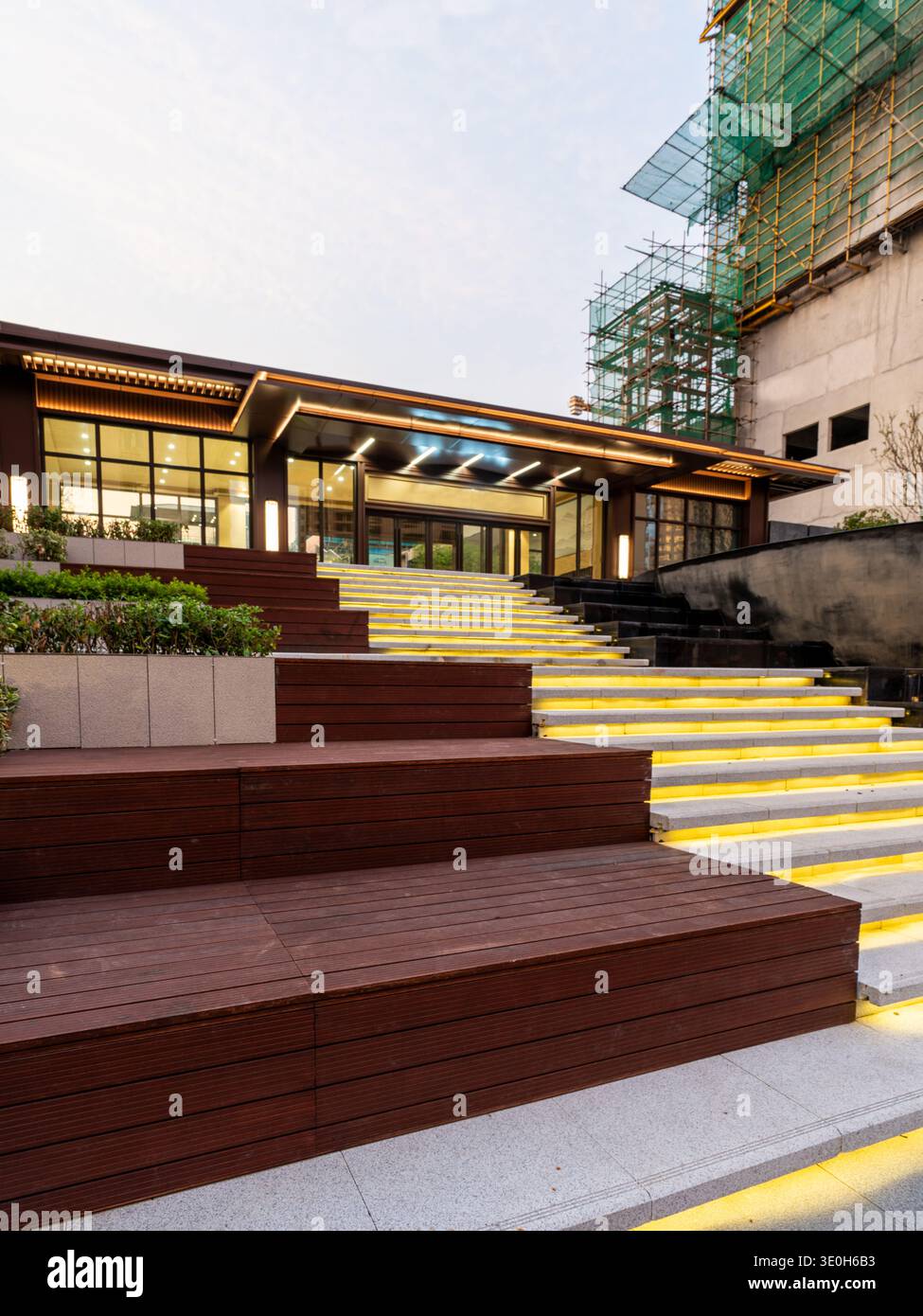 Eine breite Steintreppe mit warmer Beleuchtung unter der Treppe führt zu einem modernen Gebäudeeingang. Das Bild vermittelt großen Einstieg, Raffinesse und Architektur Stockfoto