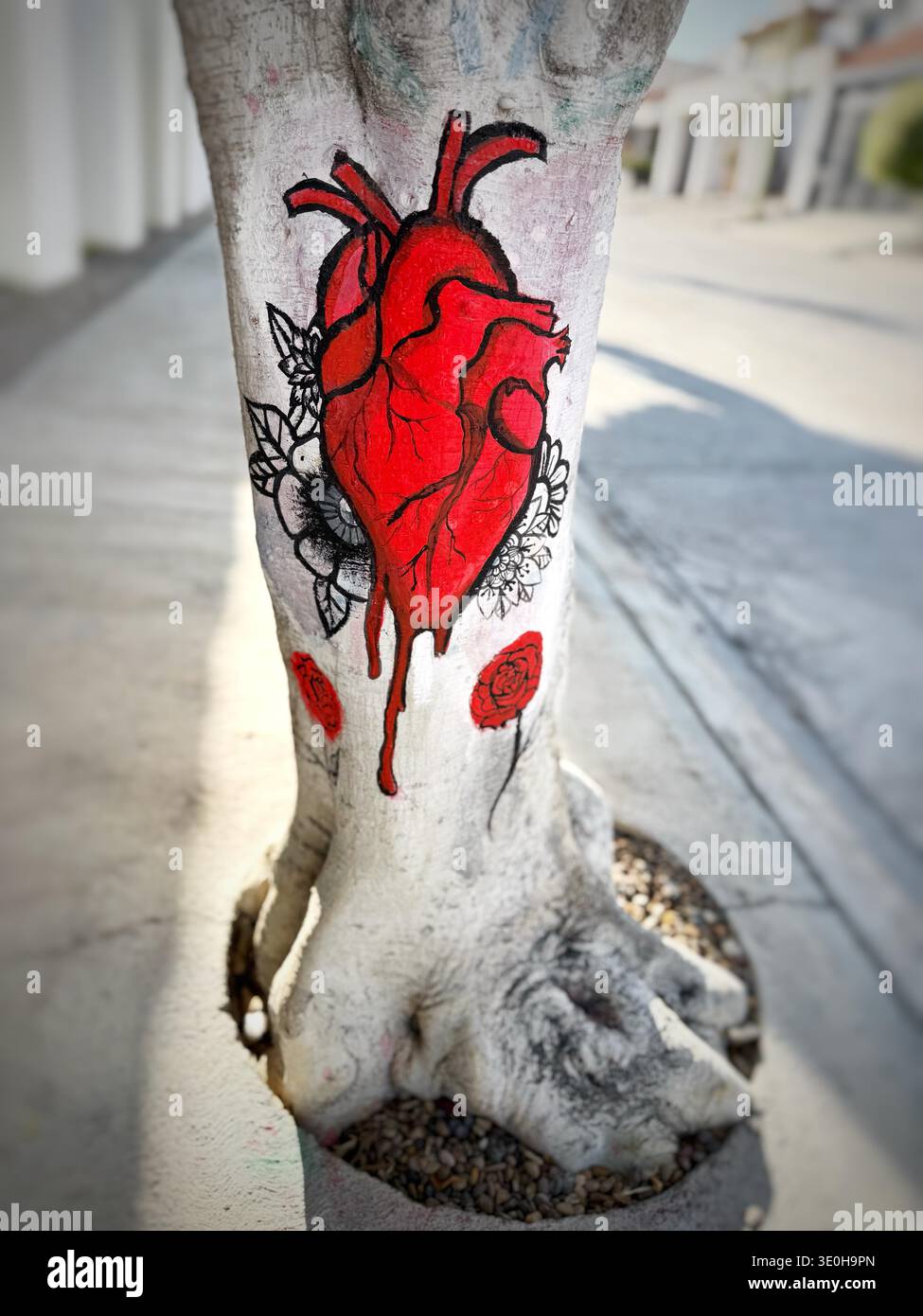Nahaufnahme eines gemalten anatomischen Herzens mit tropfender roter Farbe und Blumen auf einem Baumstamm im Freien Stockfoto