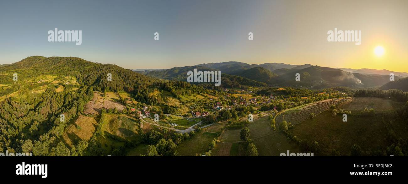 'Luftpanorama eines abgelegenen bosnischen Dorfes umgeben von Dinarischen Bergen bei Sonnenuntergang, Bosnien und Herzegowina' Stockfoto