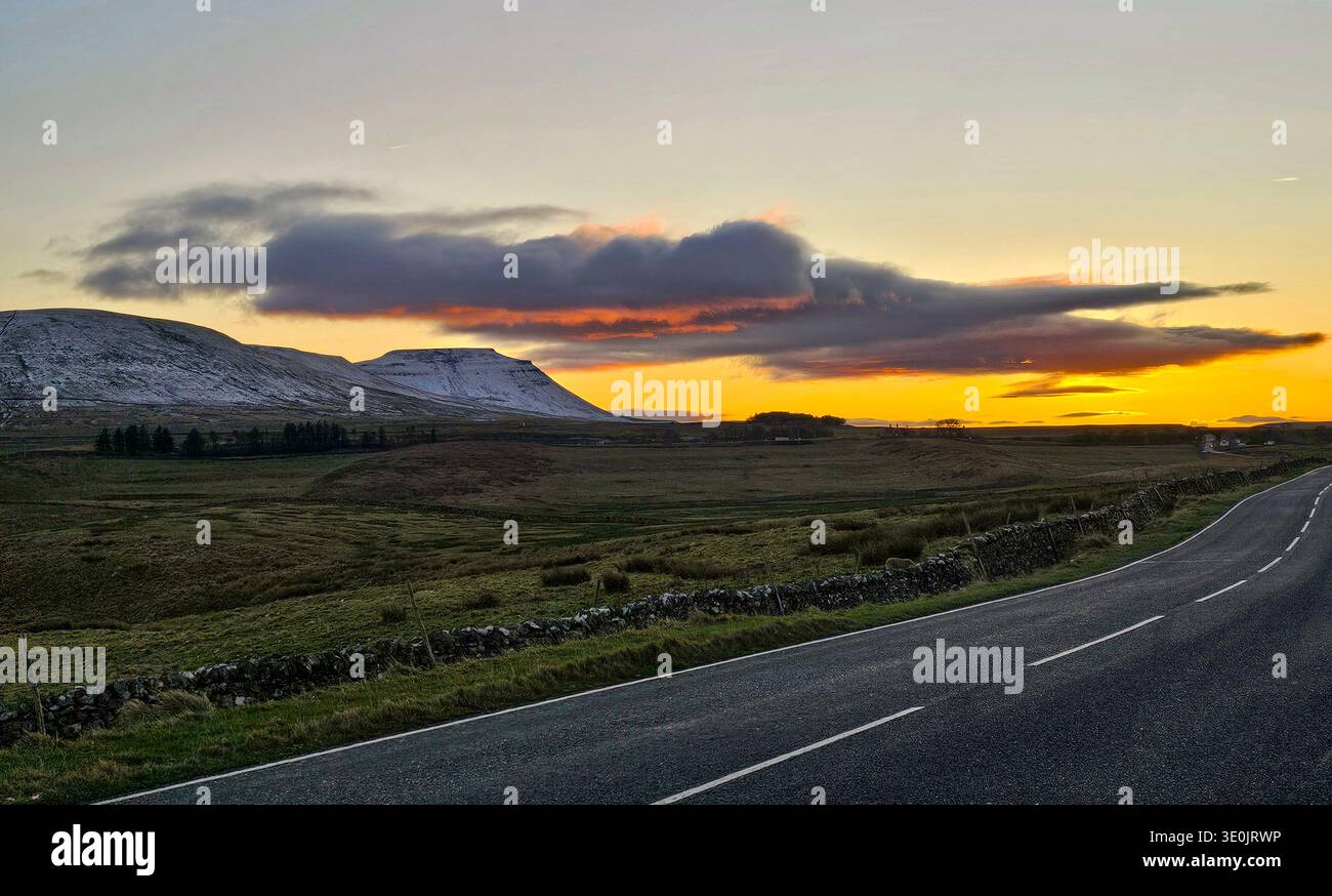 Ingleborough bei Sonnenuntergang, Yorkshire Dales National Park. Schnee auf den Fjells Ende November und ein dramatischer Himmel. Stockfoto