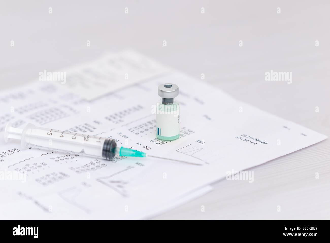 Impfstofffläschchen und Spritzen liegen auf einem medizinischen Bluttestdokument, das das Krankheitsverhütungs- und Behandlungskonzept darstellt Stockfoto