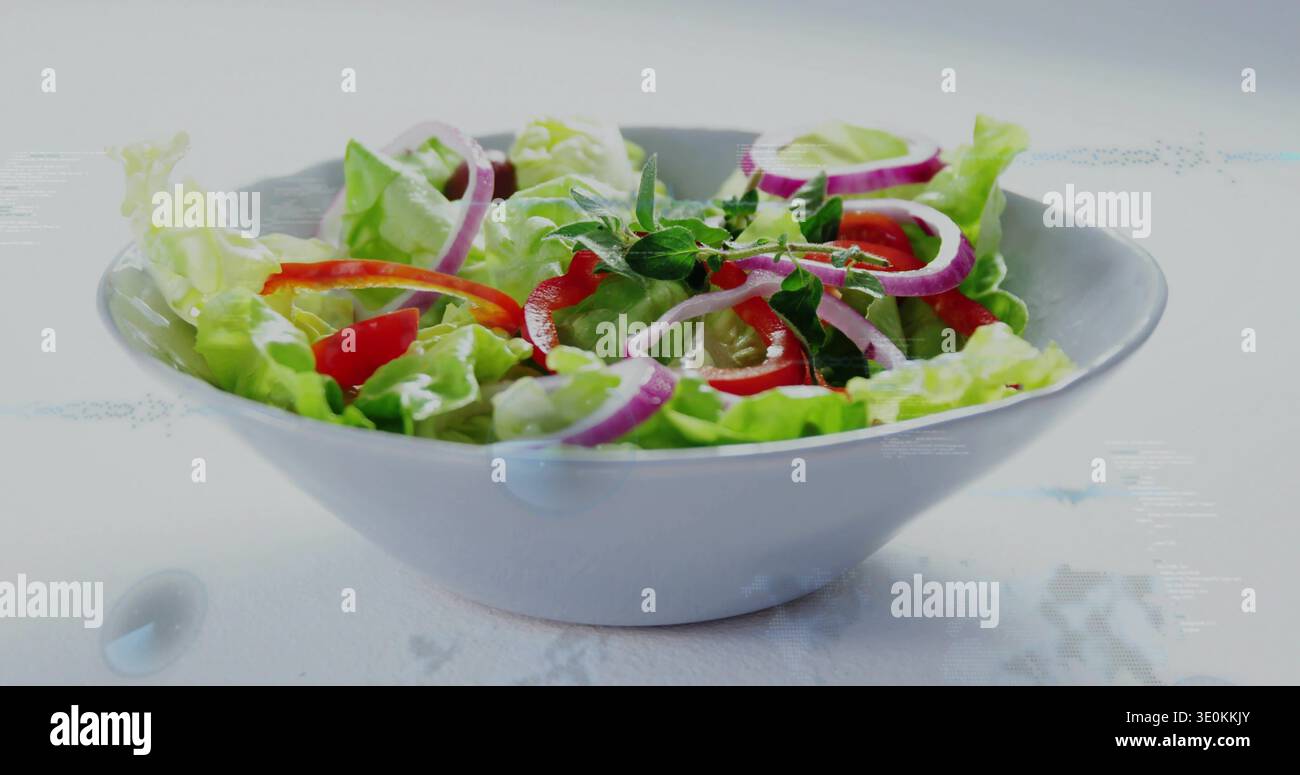 Mit weißer Keramikschale mit Salat, roter Paprika, Tomatenhälften und Kräuterzweigen auf der Tischplatte Stockfoto