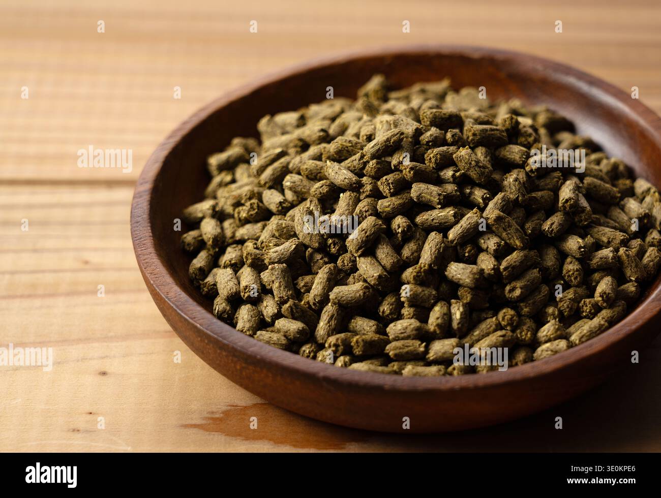 Luzerne-Pellets für Kaninchen- oder Tierfutter in einer Holzschale auf einem Holztisch mit Kopierraum Stockfoto