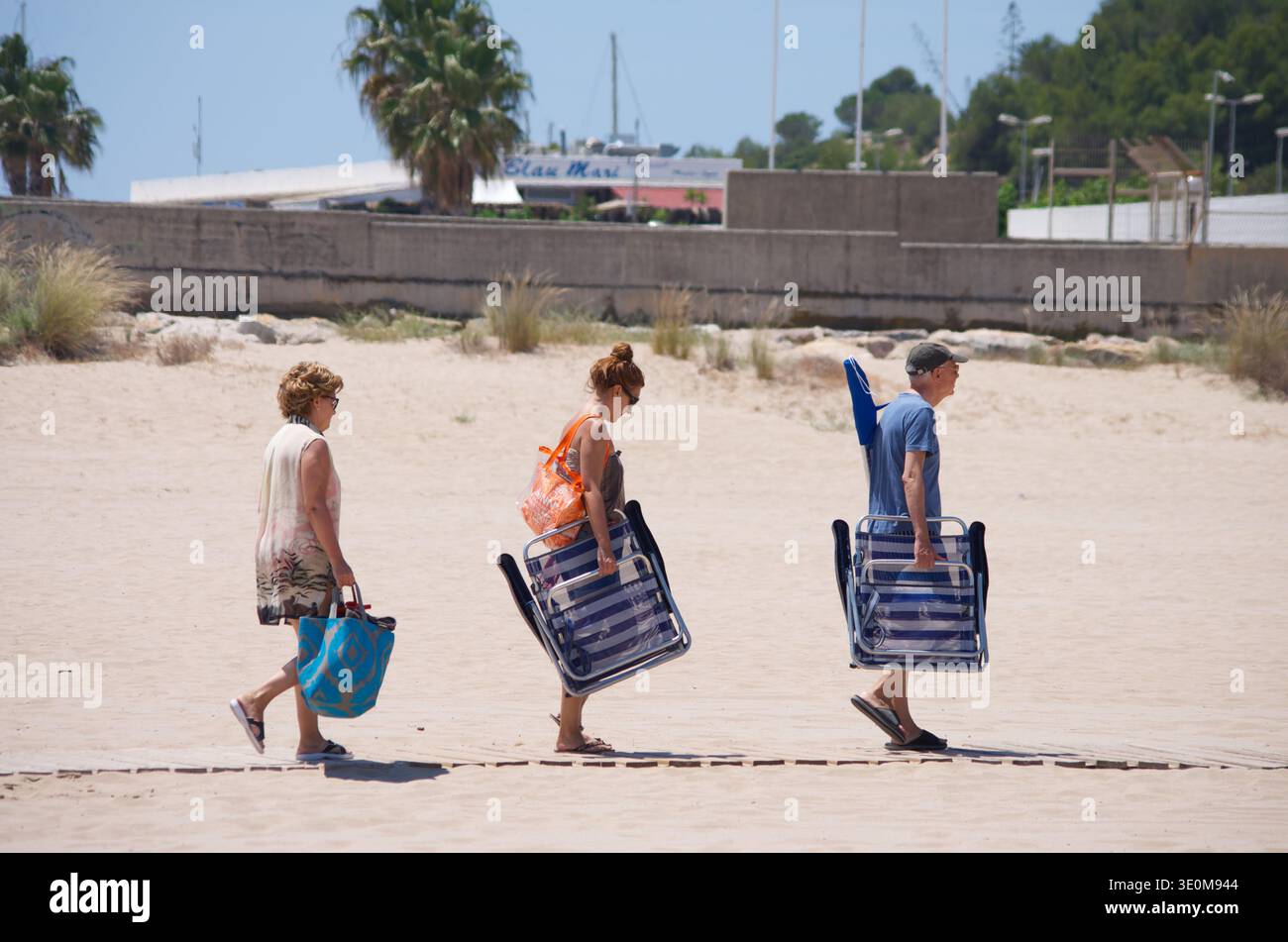Drei Personen spazieren hintereinander am Strand entlang und machen einen Tag oder ein Picknick in Katalonien, Spanien Stockfoto