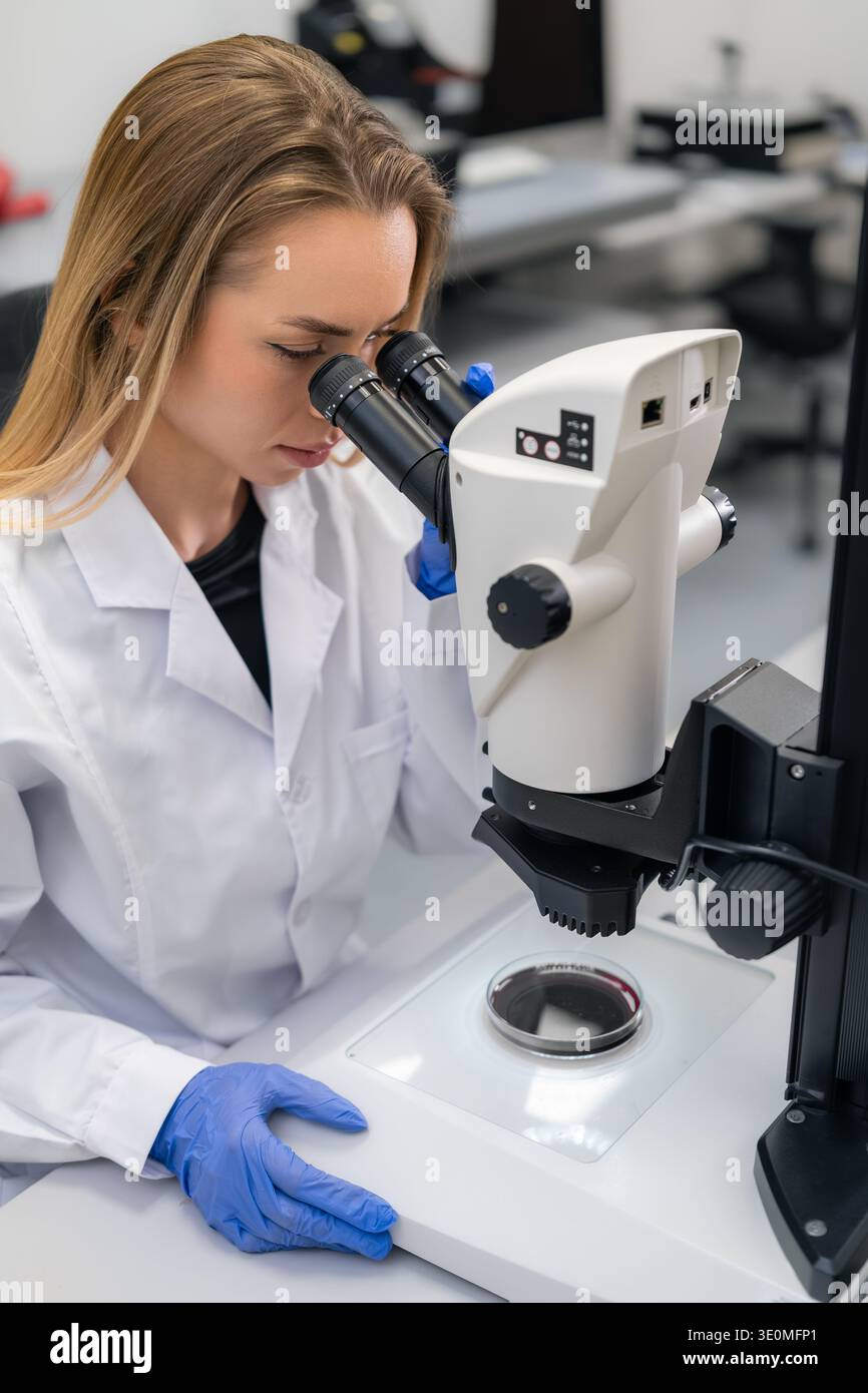 Labortechniker, der eine biologische Probe unter hochpräzisen Mikroskopen in einer modernen Forschungseinrichtung analysiert. Stockfoto