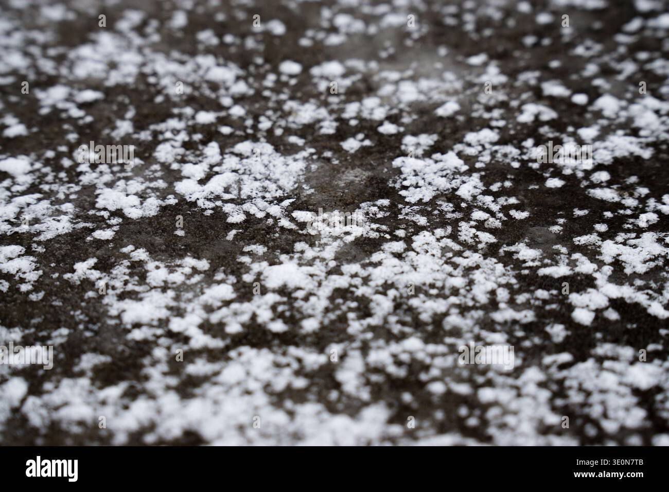 Nahaufnahme von Eis und Schnee auf einer rauen Betonoberfläche, wodurch eine frostige Textur entsteht. Stockfoto