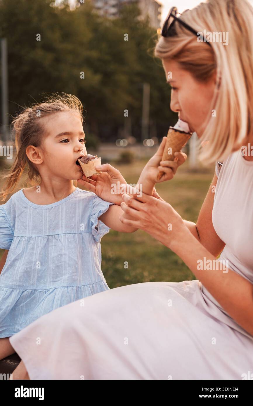 Mutter und Tochter genießen Eiskegel in einem Park Stockfoto