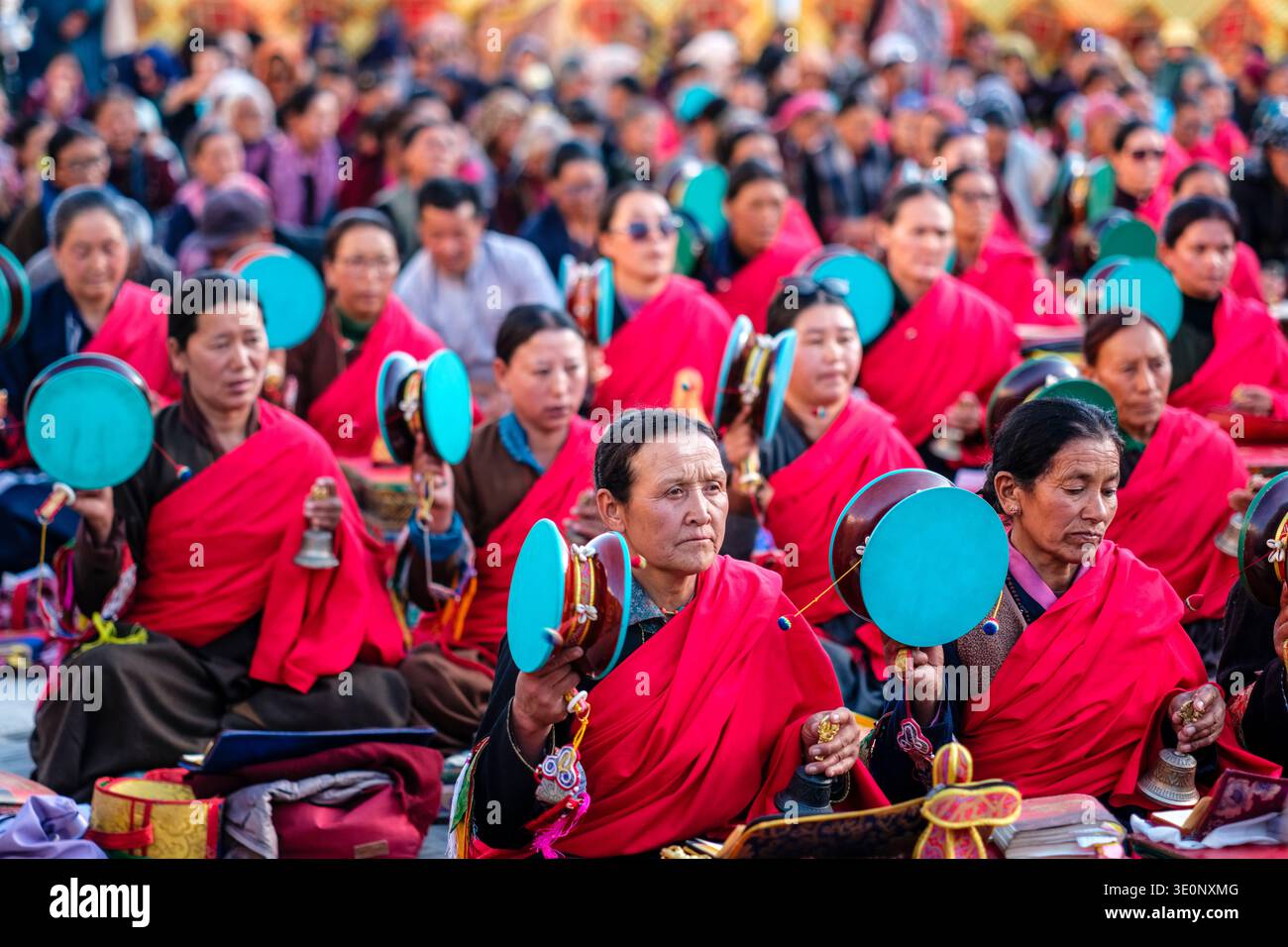 Frauen in traditioneller roter Kleidung spielen zeremonielle Handtrommeln und Glocken während einer religiösen Versammlung im Dorf Panamik. Stockfoto