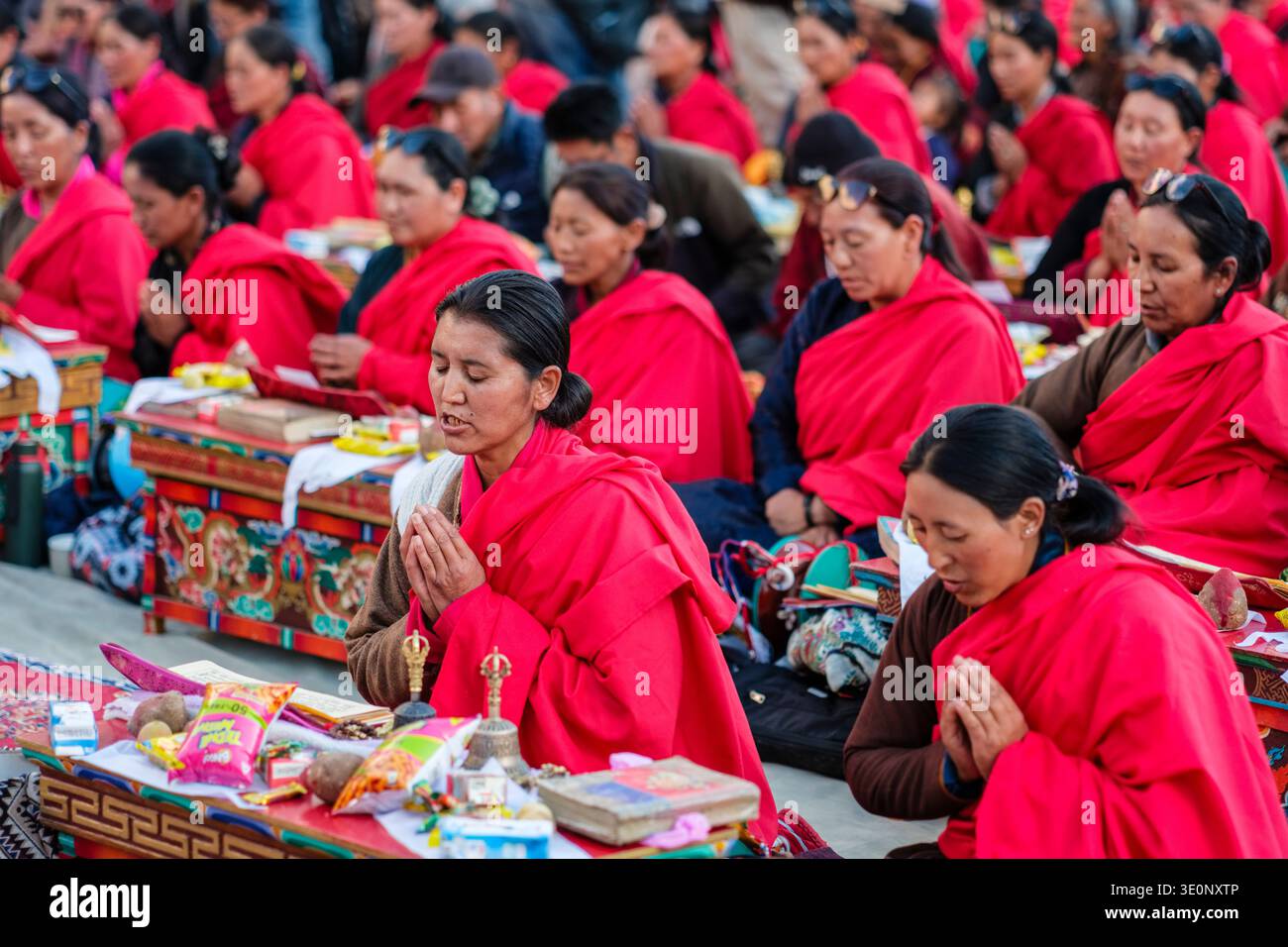 Eine Gruppe von Frauen in traditioneller Kleidung sitzt mit gefalteten Händen im Gebet während einer religiösen Veranstaltung in Panamik. Stockfoto