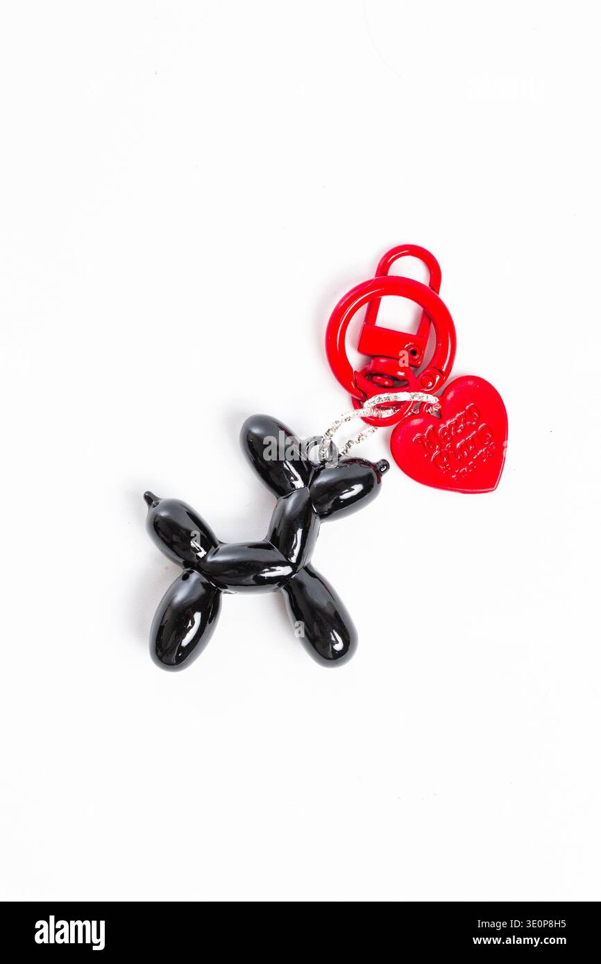 Eleganter schwarzer Schlüsselanhänger mit Ballon und rotem Herzanhänger. Perfektes Accessoire für den täglichen Gebrauch und Geschenke. Stockfoto