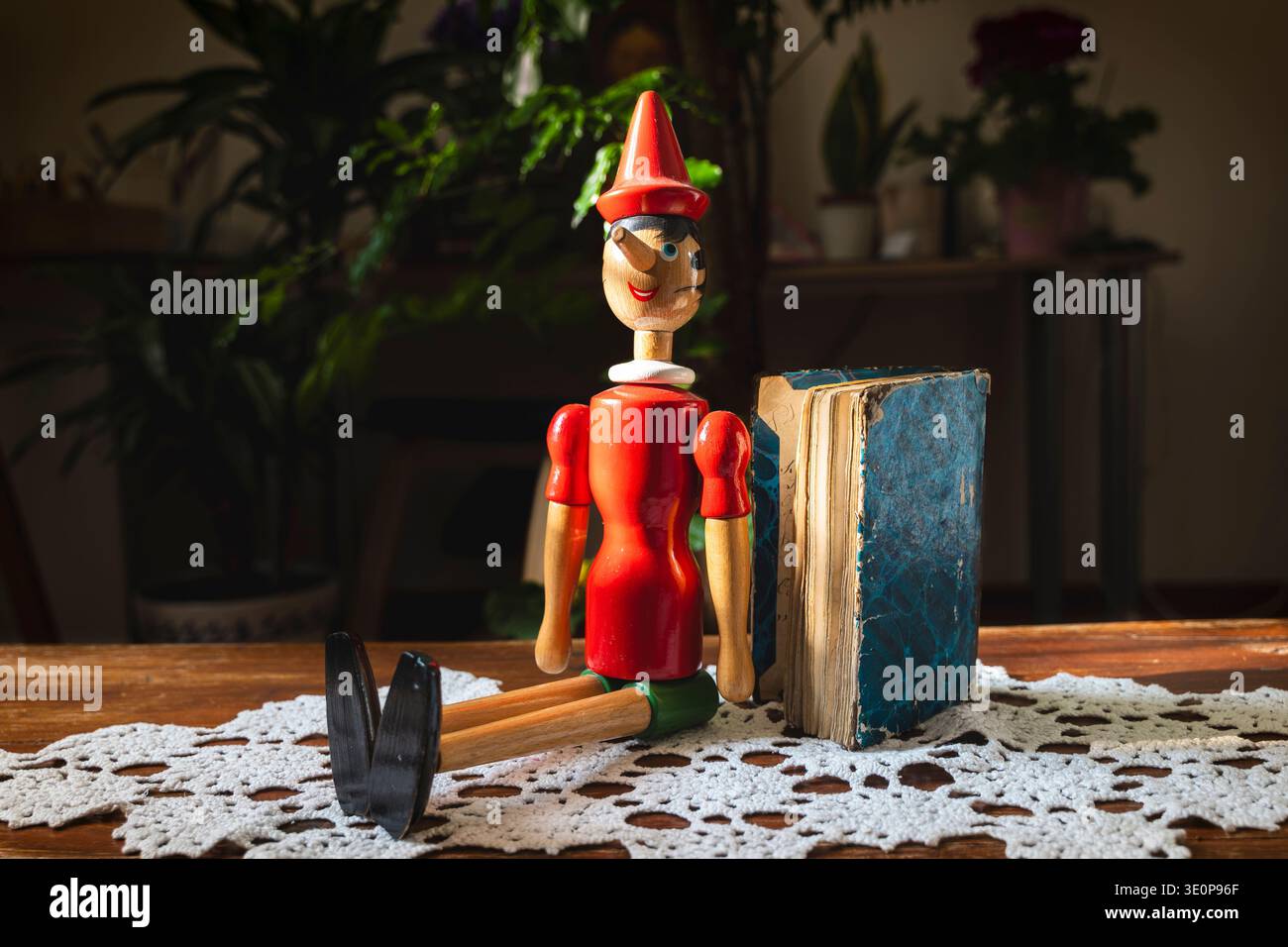Klassische Märchenpuppe aus Holz von pinocchio, die neben einem alten Buch sitzt und Themen von Lügen und Geschichten erzählt Stockfoto