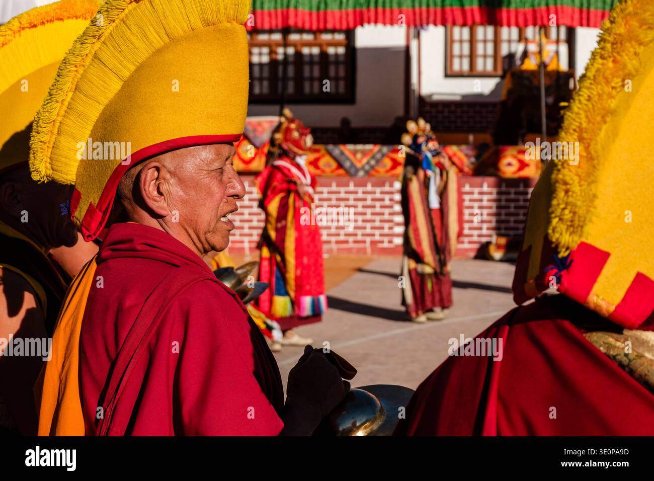 Ein Gelugpa-Mönch in einem traditionellen gelben Haubenhut ertönt während der zeremoniellen Tänze des Diskit Gustor Zimbeln. Leh District Union Territory von L Stockfoto