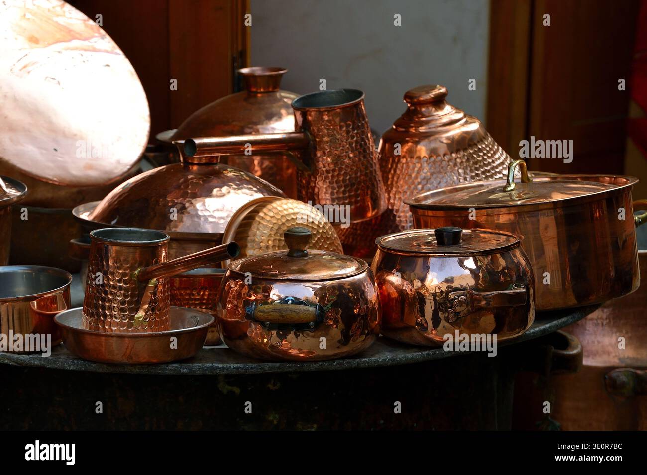 Glänzende Kupferkochtöpfe und -Utensilien, die auf dem Markt ausgestellt werden, mit reichhaltiger metallischer Textur und Wiederholung Stockfoto
