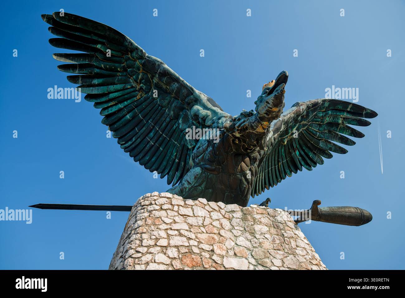 Bronze-Turul-Statue mit Kondrail und Flugzeug im Blauen Himmel. Historisches ungarisches mythologisches Vogeldenkmal mit modernem Kontrast zum Flugweg. Stockfoto