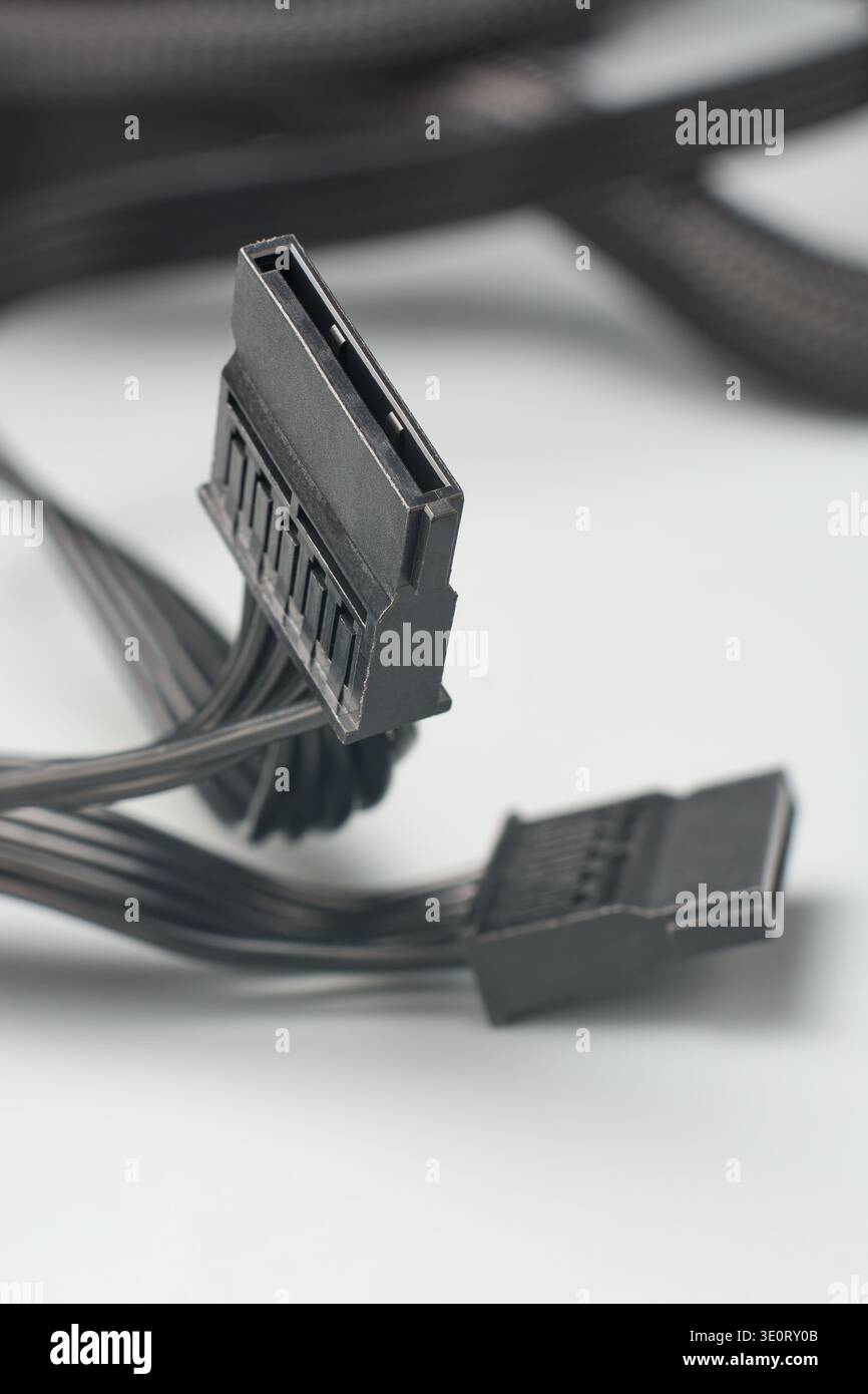 Schwarze sata-Netzsteckverbinder auf grauer Oberfläche, mehrere Flachbandkabel zur Datenspeicherung, Seitenansicht mit Weichfokus, Computer-Montage und -Reparatur Stockfoto