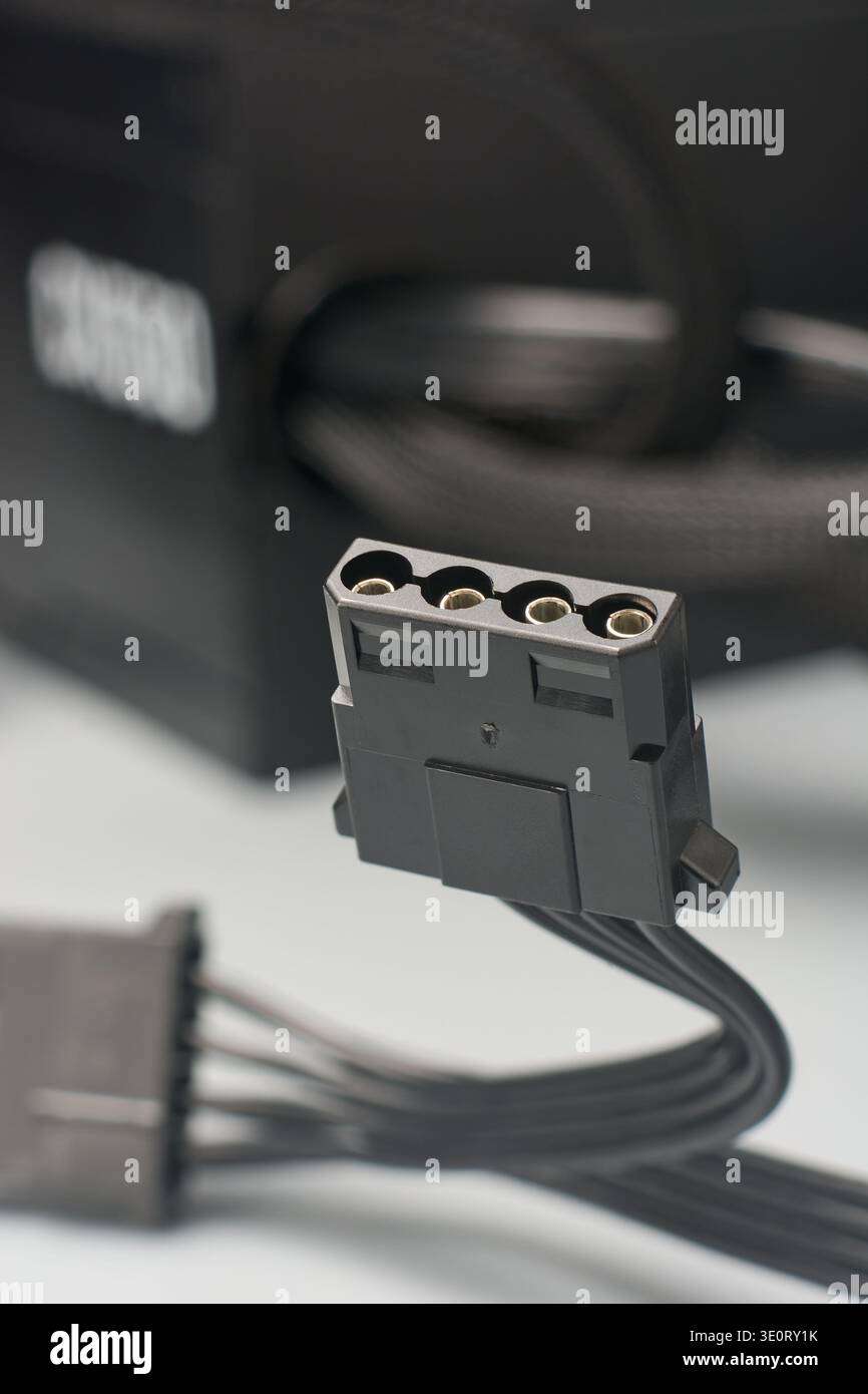 4-poliger schwarzer molex-Netzstecker auf grauer Oberfläche, Peripheriegerätebuchse mit Metallstiften, Seitenansicht mit Softfokus, Hardwarenetzteil Stockfoto