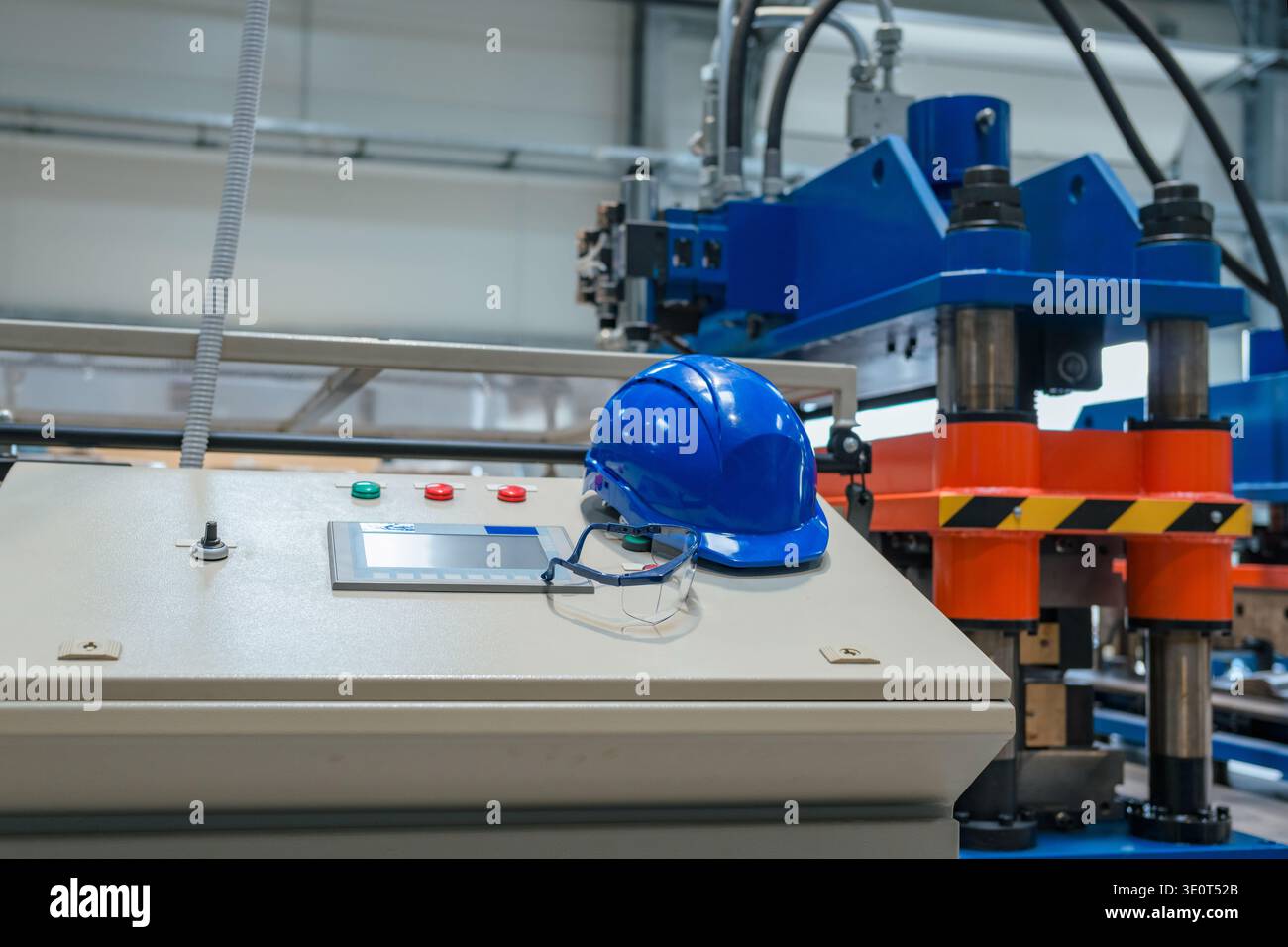 Automatisierte Maschinen arbeiten mit Schutzhelm an einer Produktionslinie in einem modernen Fertigungswerk ohne Anwesenheit von Personen. Stockfoto