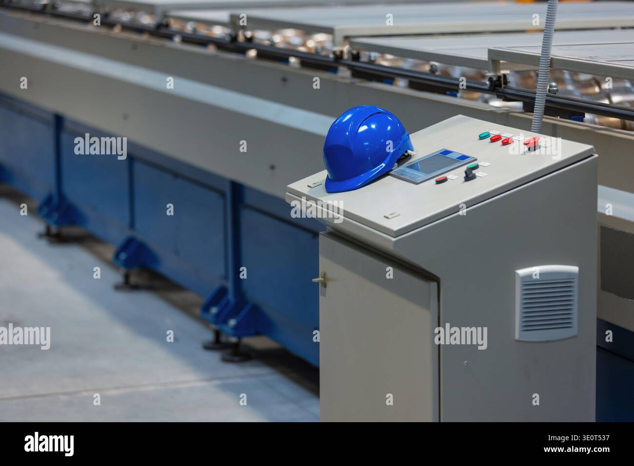 Die automatisierte Produktionslinie arbeitet in einem Produktionswerk mit Industriemaschinen und Schalttafel mit Sicherheitsausrüstung im Werk. Stockfoto