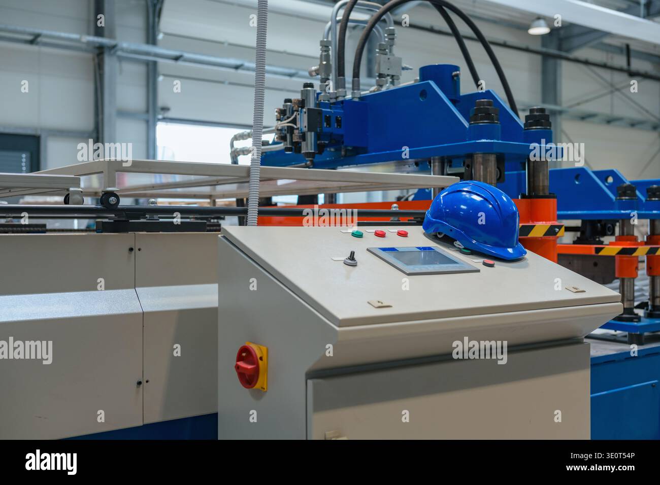 Eine moderne Produktionslinie mit verschiedenen Industriemaschinen und Schutzhelm. Das Gerät ist in Betrieb, ohne dass sich Personen aufhalten. Stockfoto