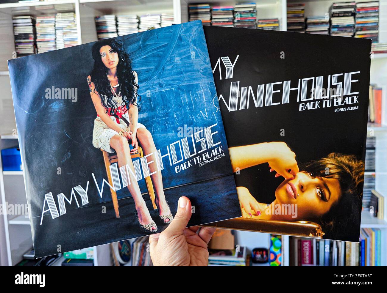 Hand hält zwei Amy Winehouse Back to Black Vinyl-Alben und zeigt das Original- und Bonusalbum-Cover in einer eigenen Bibliothek. Stockfoto