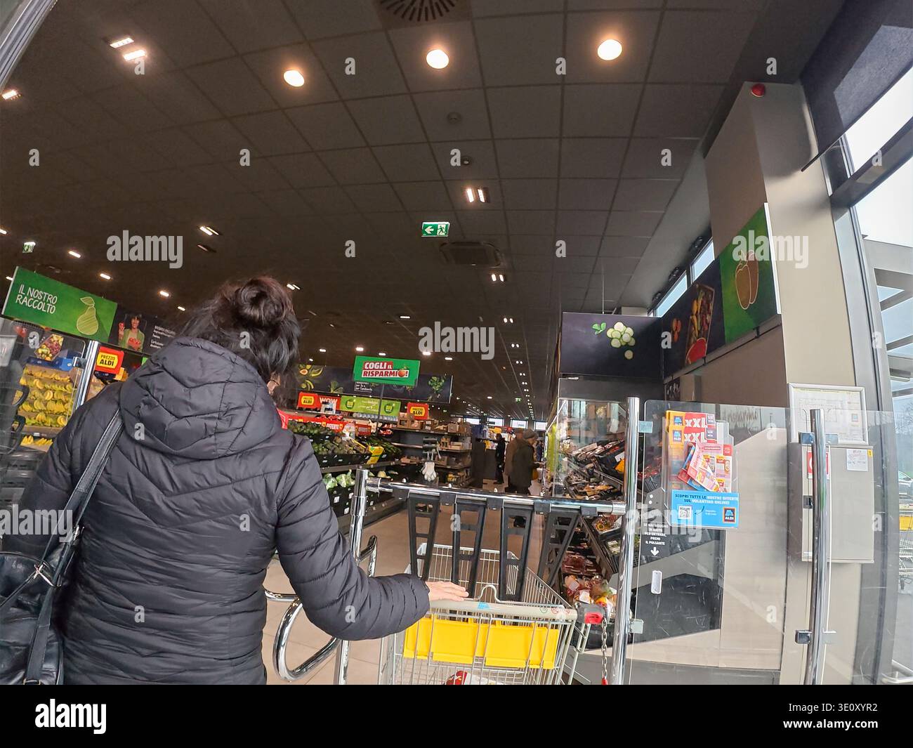 Cremona, Italien - 9. März 2026 Eine Frau mit Haaren in einem Brötchen schiebt einen Einkaufswagen durch die Gänge eines Aldi Discounter in Italien, Surunde Stockfoto
