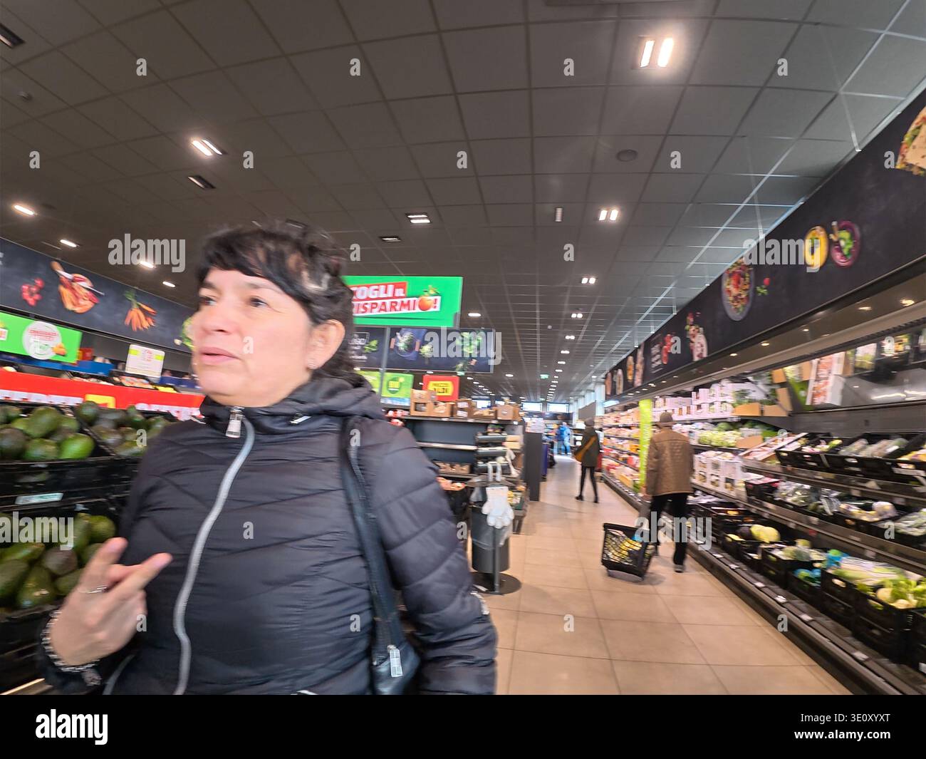 Cremona, Italien - 9. März 2026 Eine Frau durchstöbert den Obst- und Gemüsegang in einem hell erleuchteten Aldi-Geschäft und wählt Produkte für ihre Lebensmittel aus Stockfoto