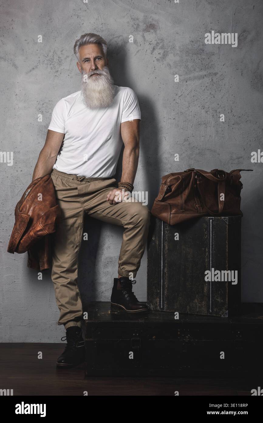 Stilvoller und hübscher bärtiger älterer Mann, der im Studio posiert Stockfoto
