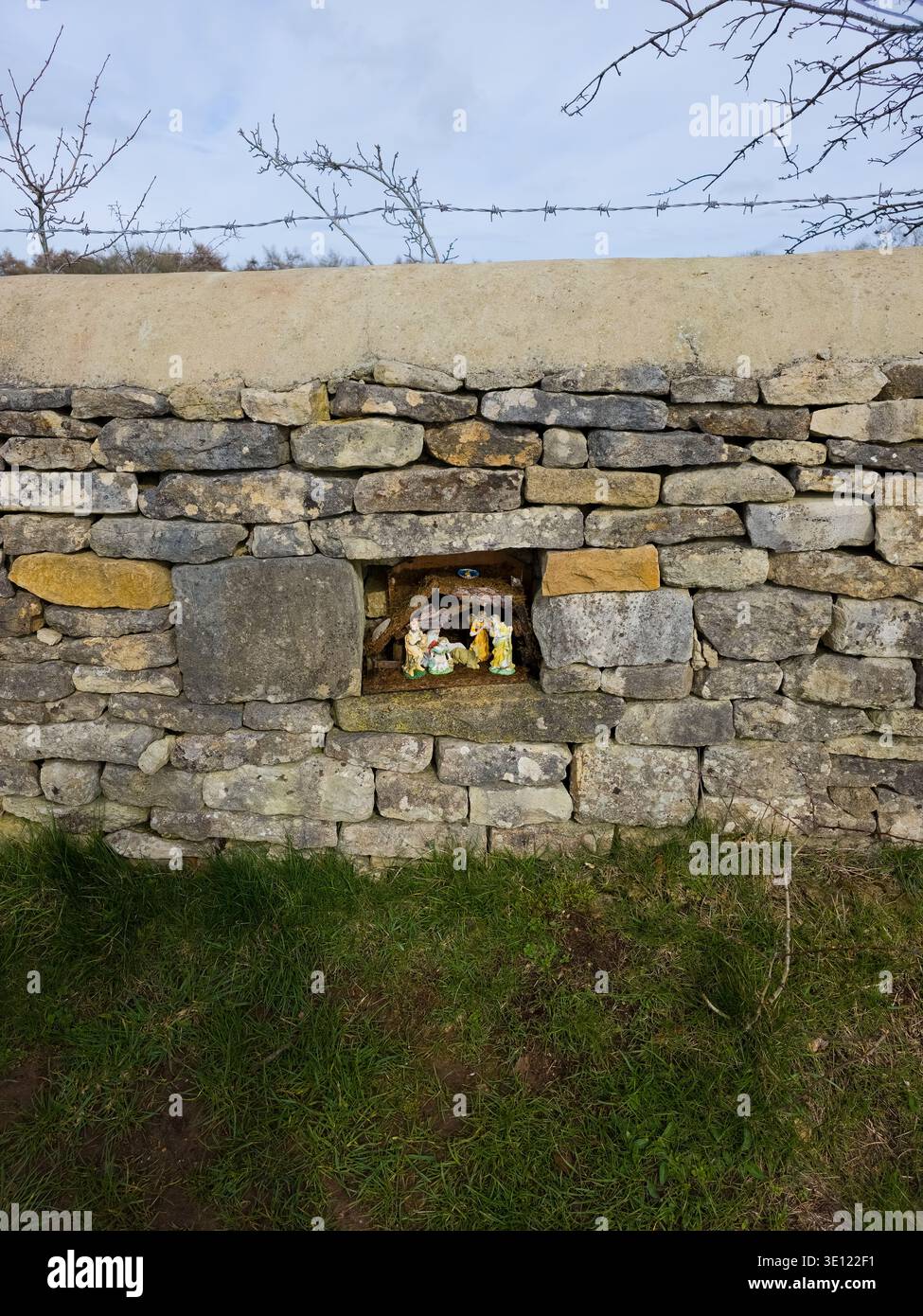 Roadside Shrine Grotto in Cotswold Stone Wall mit religiösen Figuren, Stroud Area, Gloucestershire, England Stockfoto