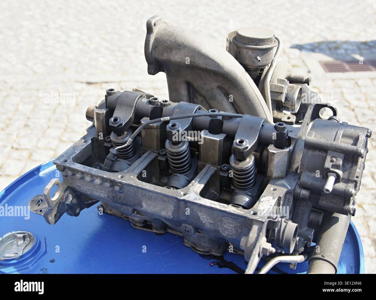 Öffnen Sie den Motorblock, der auf einem blauen Zylinder platziert ist, und zeigen Sie seine inneren Komponenten, Federn und Kipphebel Stockfoto