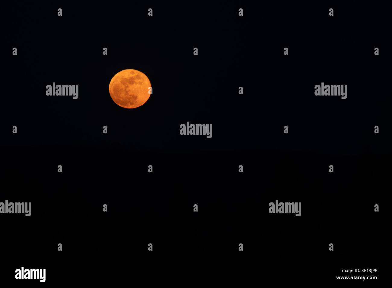 Großer orangefarbener Vollmond im oberen linken Drittel des Rahmens vor einem dunklen Nachthimmel Stockfoto