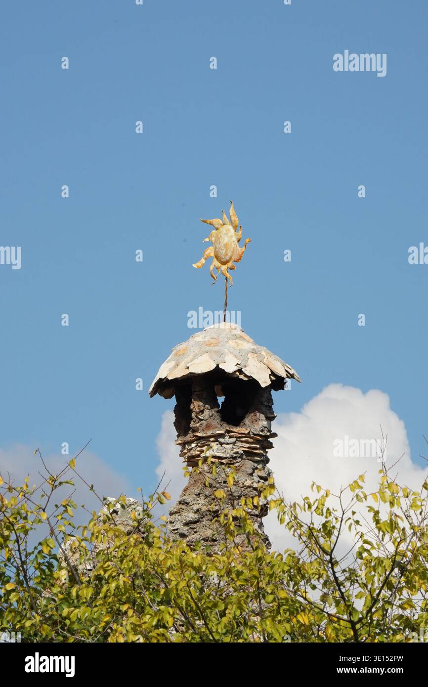 Steinkamin mit Metallsonnenschmuck gegen den blauen Himmel Stockfoto