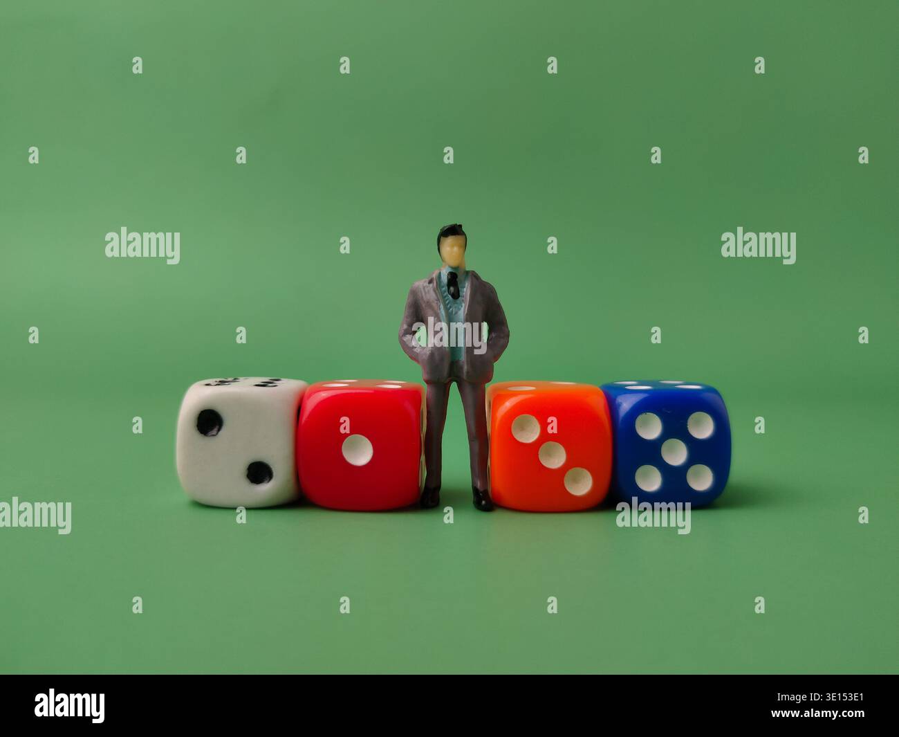 Dieses Bild zeigt eine Miniaturfigur eines Geschäftsmannes, der zwischen bunten Würfeln steht. Stockfoto