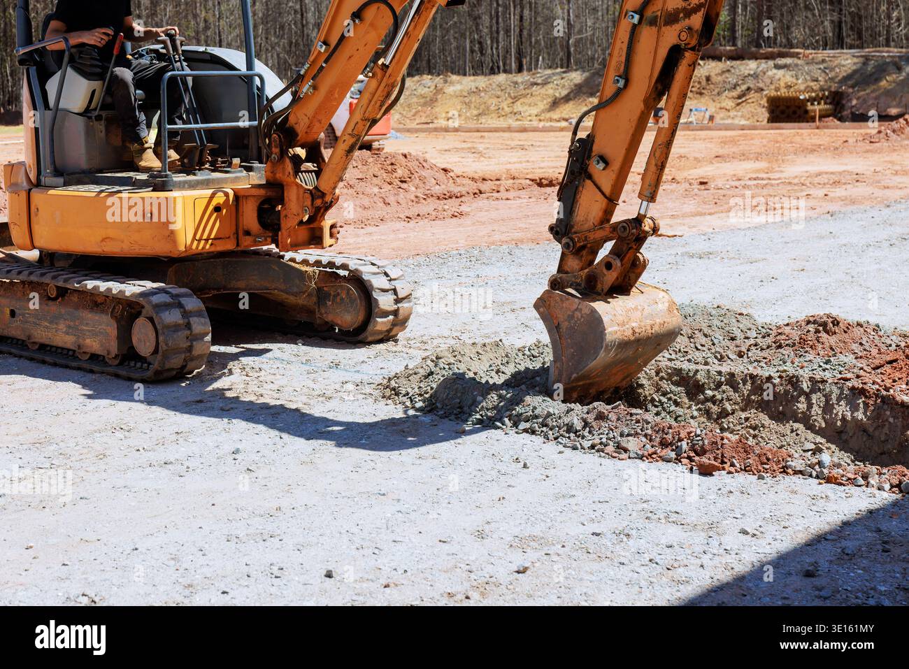 Der Arbeiter bedient einen Bagger, um Graben auf der Baustelle zu graben Stockfoto