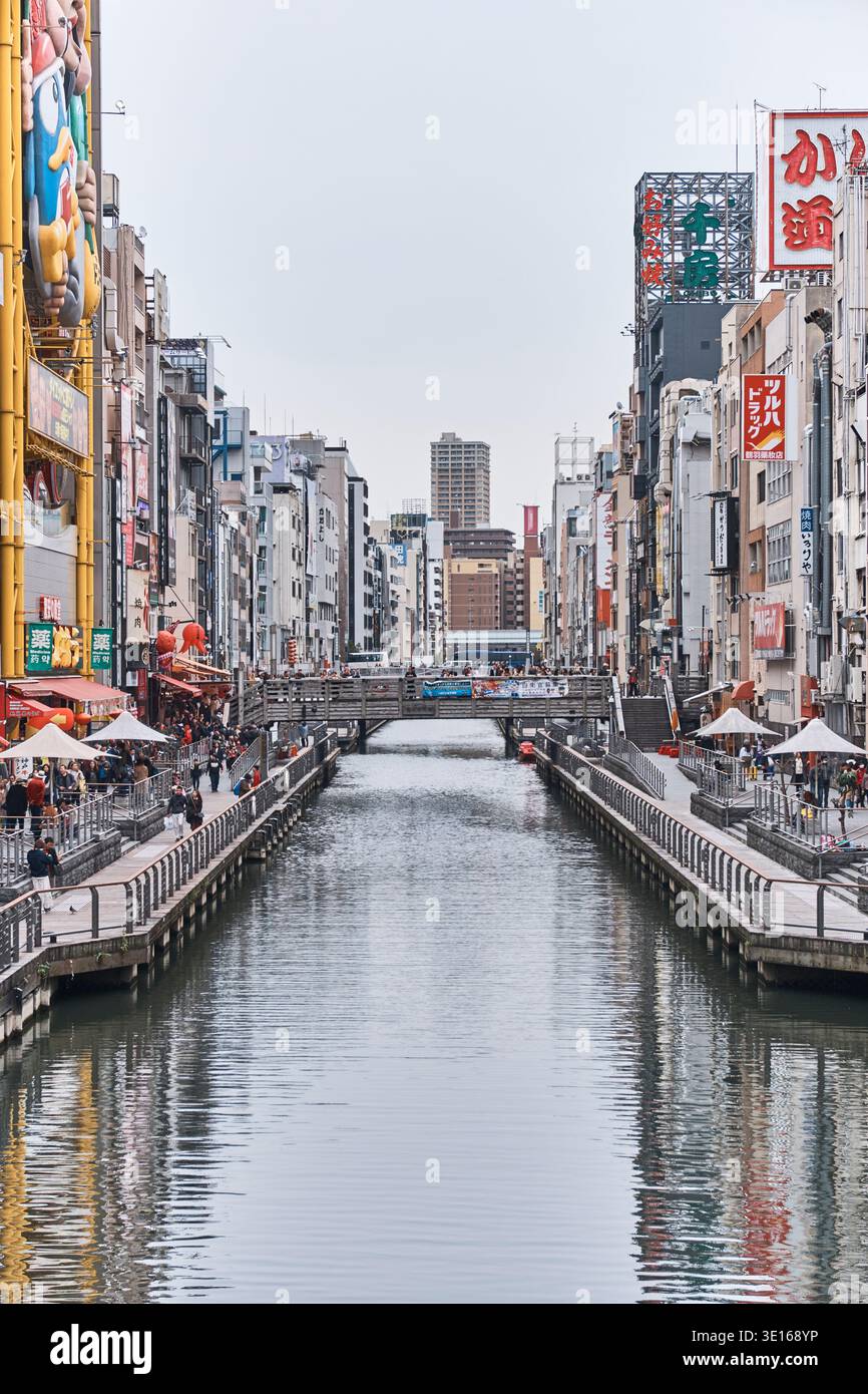 Symmetrischer Blick entlang des Dotonbori-Kanals durch ein dichtes Geschäftsviertel. Stockfoto