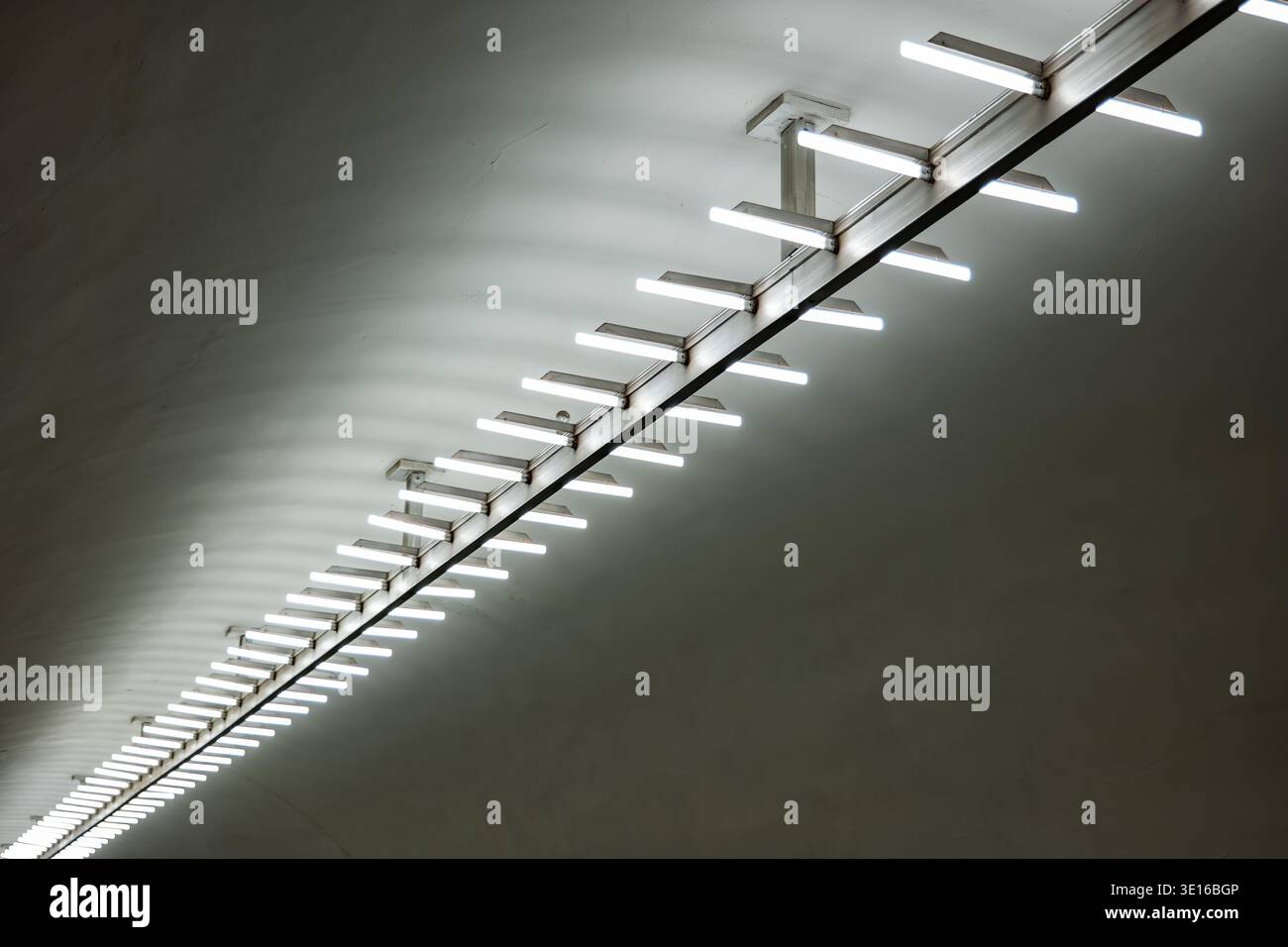 Lange Reihe von Leuchtstofflampen, die eine Betonarchitektur beleuchten Stockfoto
