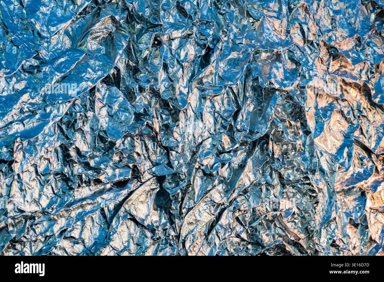 Die zerknitterte Aluminiumfolie erzeugt einen abstrakten metallischen Hintergrund mit blauem Licht Stockfoto