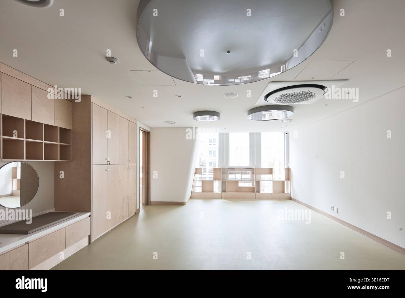 Warme Familien-Lounge oder Klassenzimmer mit Holzfußboden und eingebautem Stauraum. Stockfoto